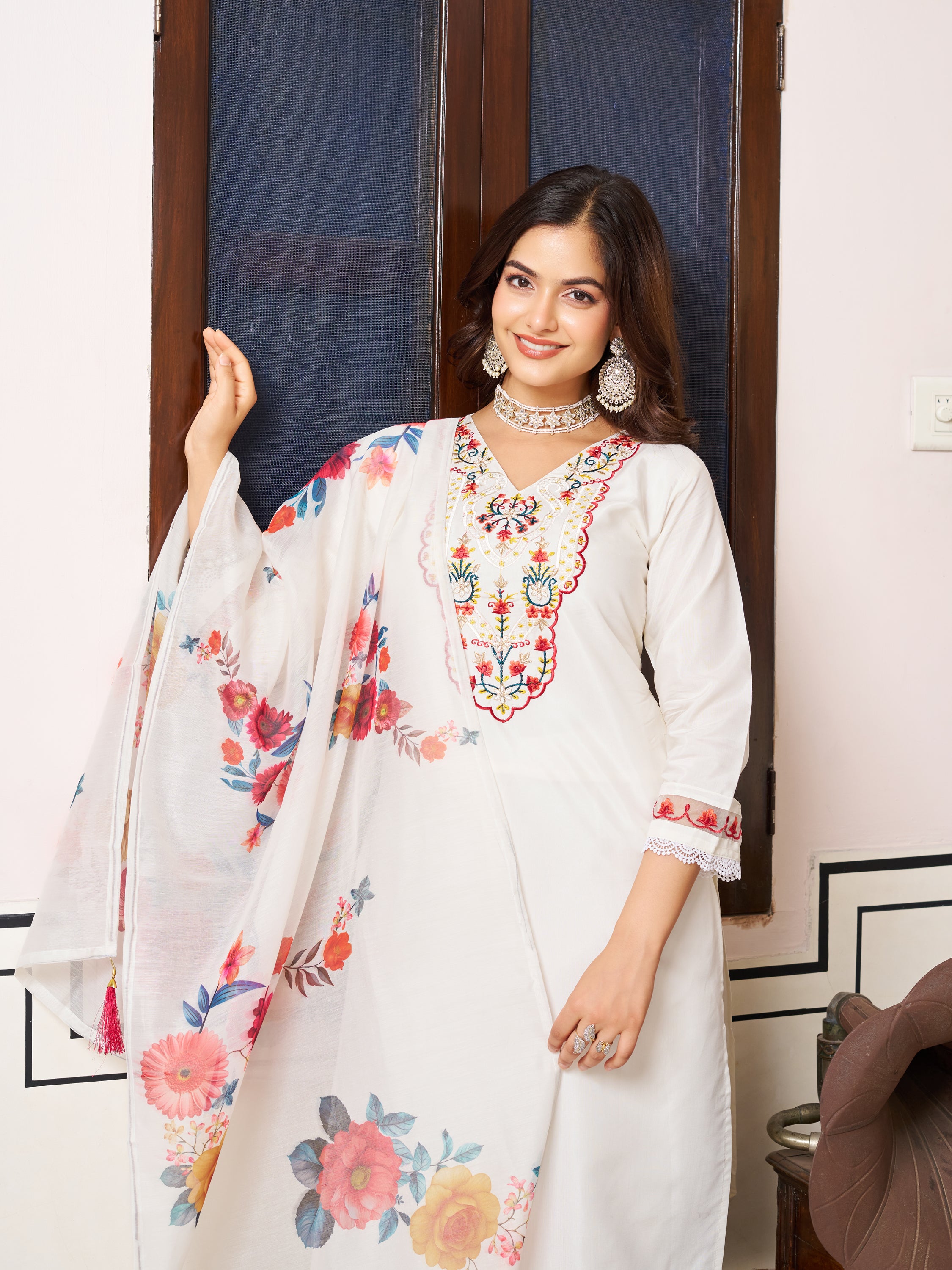 Woman standing by a window, showcasing the detailed embroidery of the white Chanderi silk kurta set.