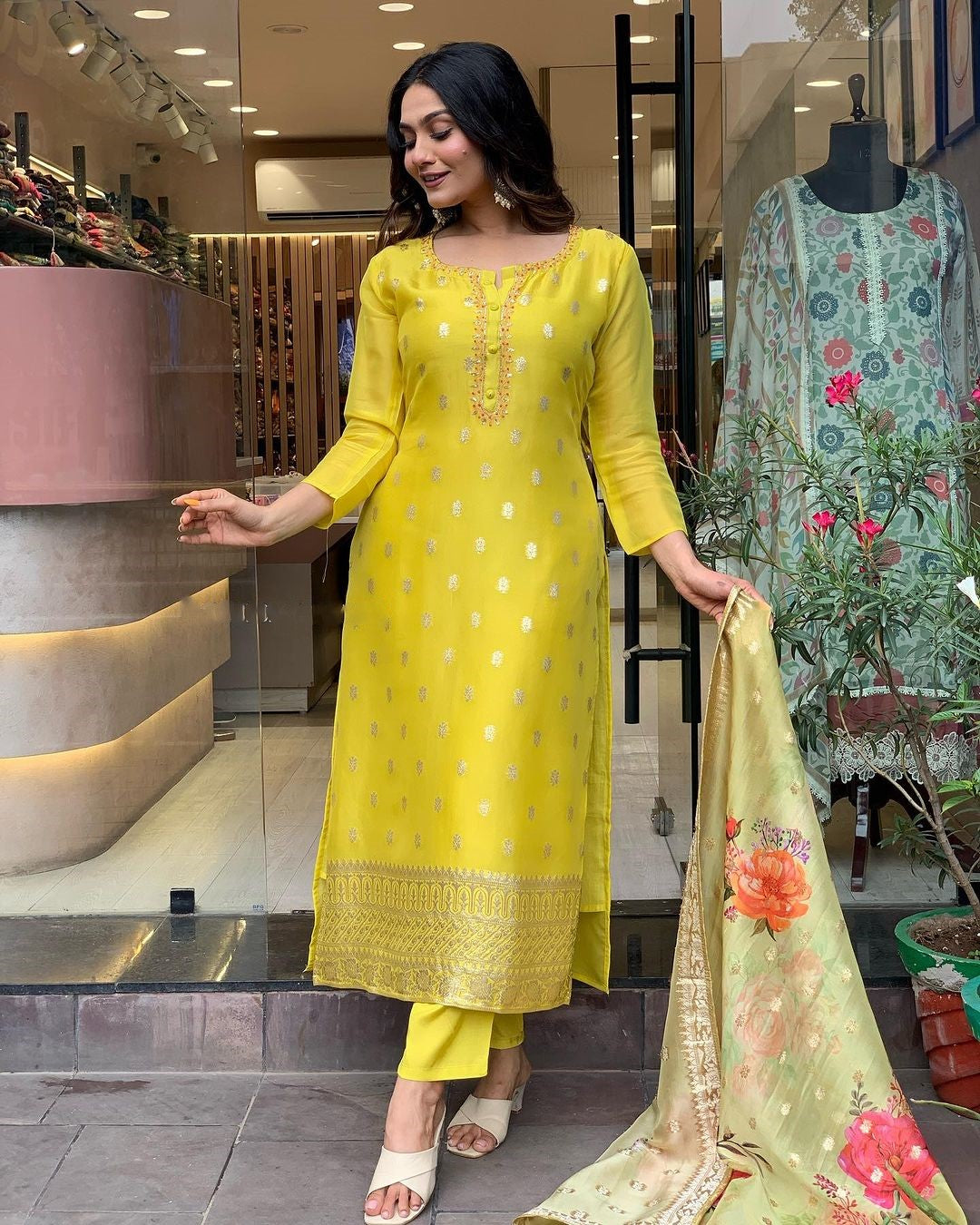 Woman in yellow kurti with gold embroidery, holding a jacquard dupatta with a beautiful digital floral print.