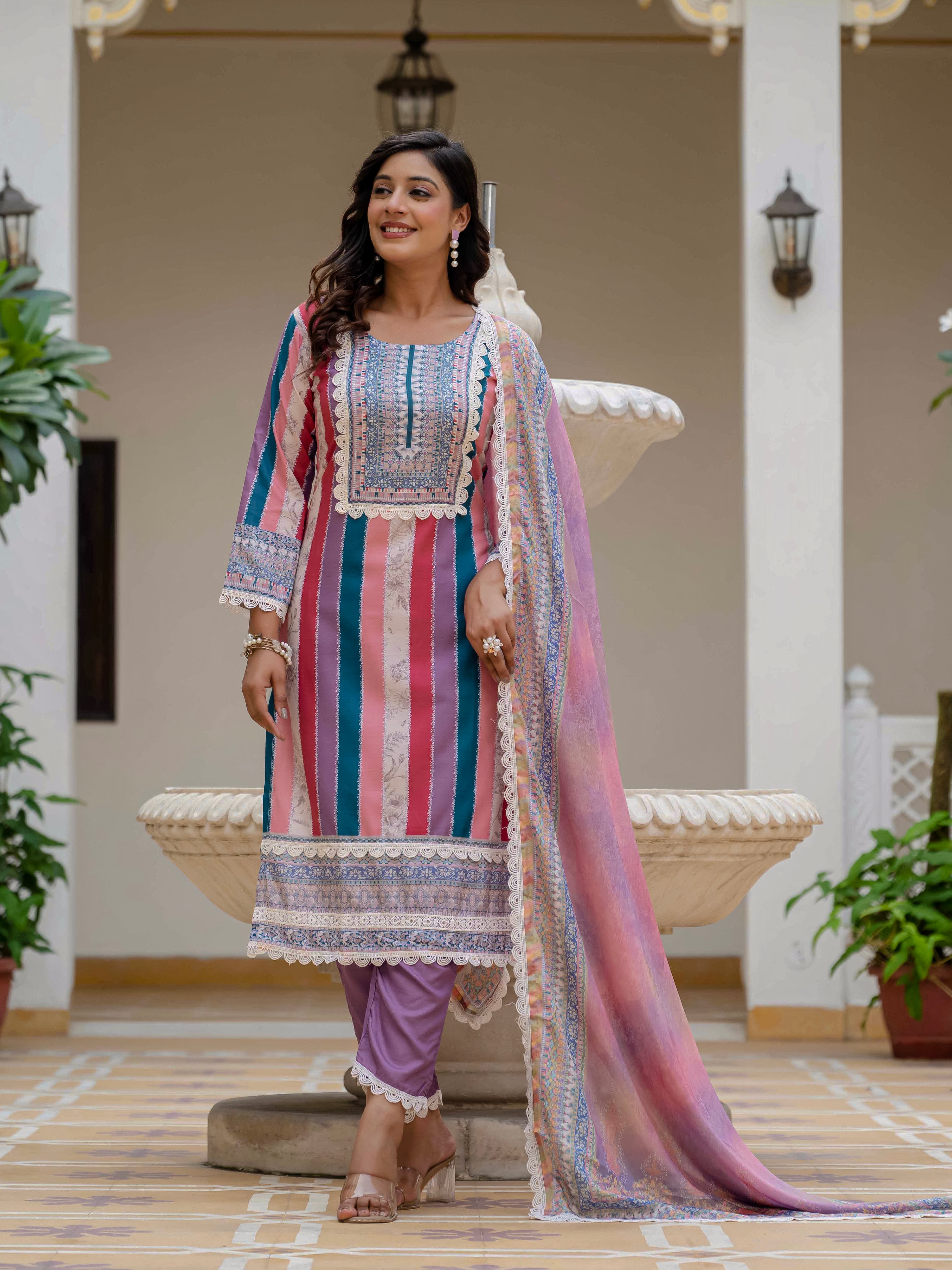 Model smiling in Laila Pink Kurta Set, standing confidently by an ornate white fountain.