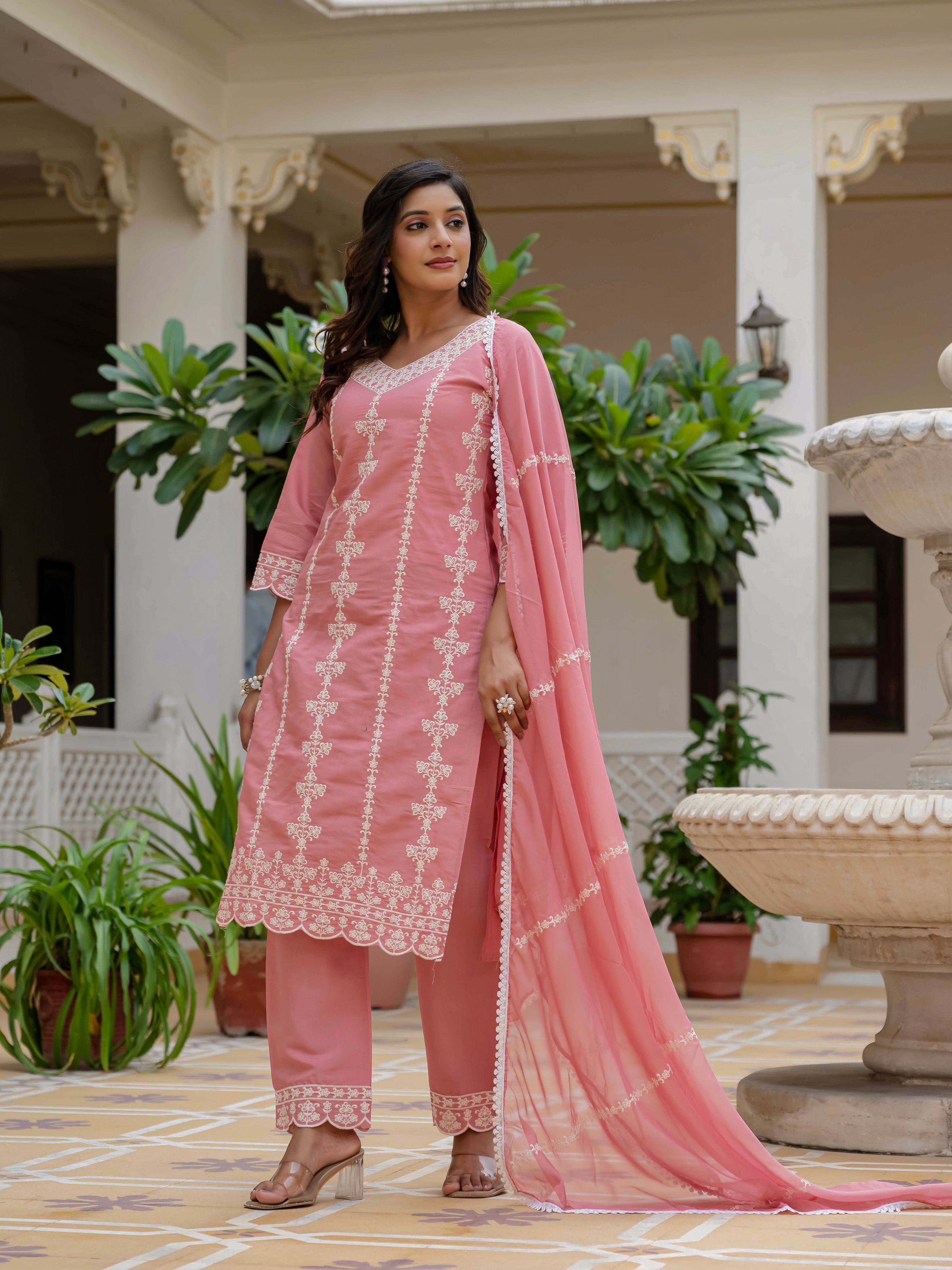 Side profile of a woman confidently posing in a rose pink embroidered kurti set with a gracefully draped organza dupatta, highlighting the outfit's flow and silhouette.