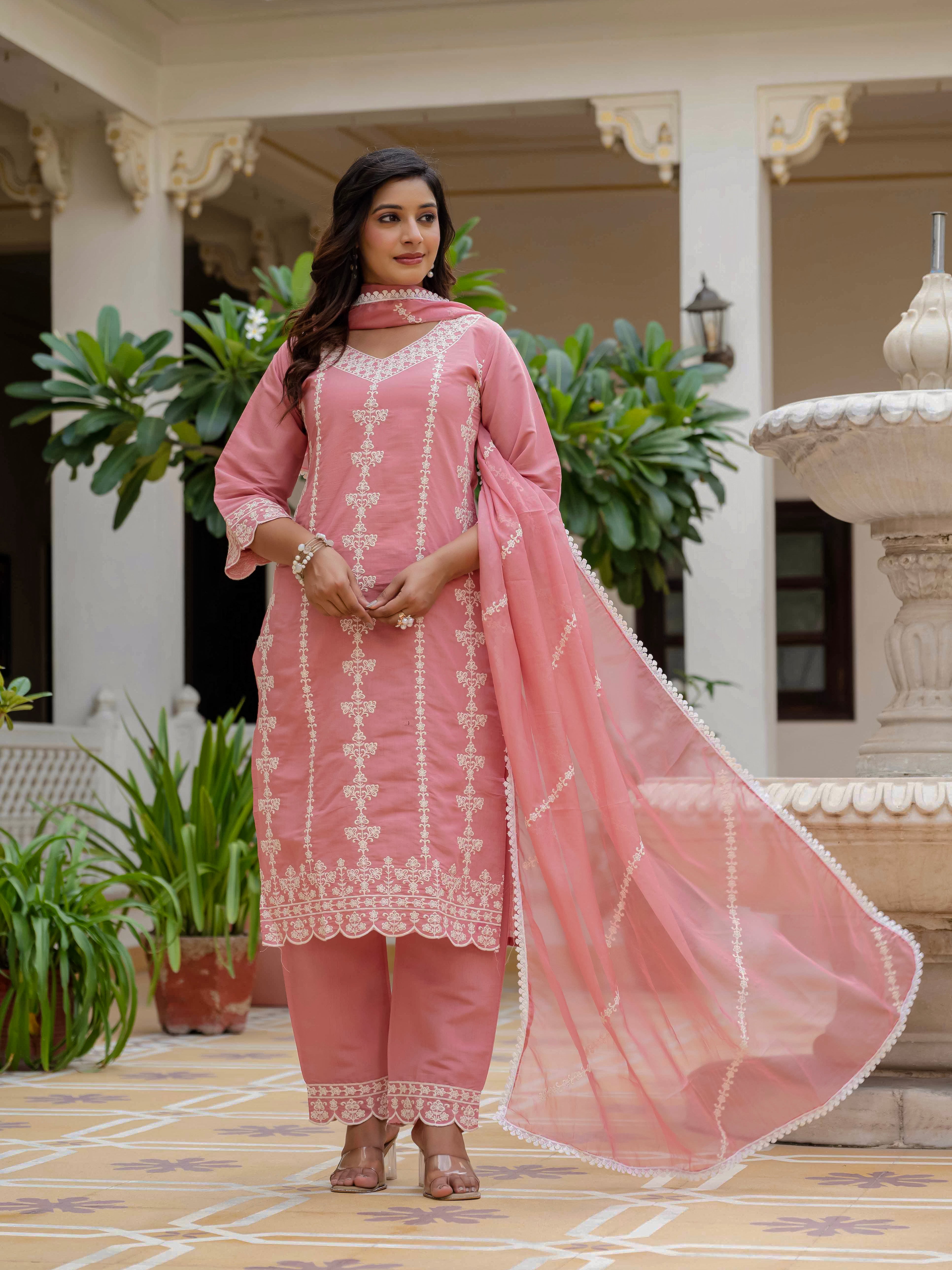 Woman showcasing the rose pink Roman silk kurti set with the organza dupatta draped over her shoulders, looking poised and elegant in an outdoor setting.
