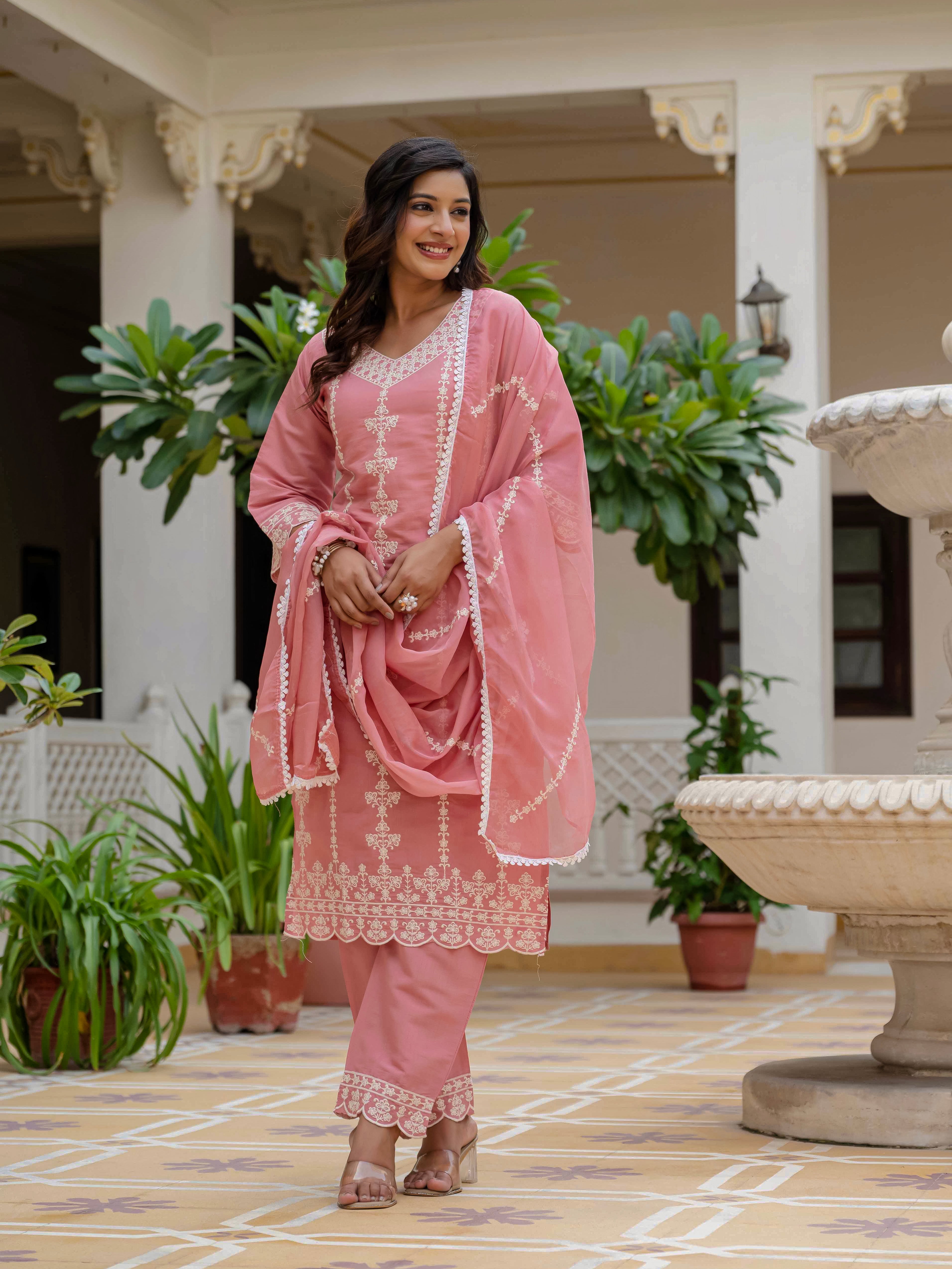 Woman adjusting her rose pink Roman silk kurti and organza dupatta, displaying the versatility and style of the ethnic ensemble with movement.