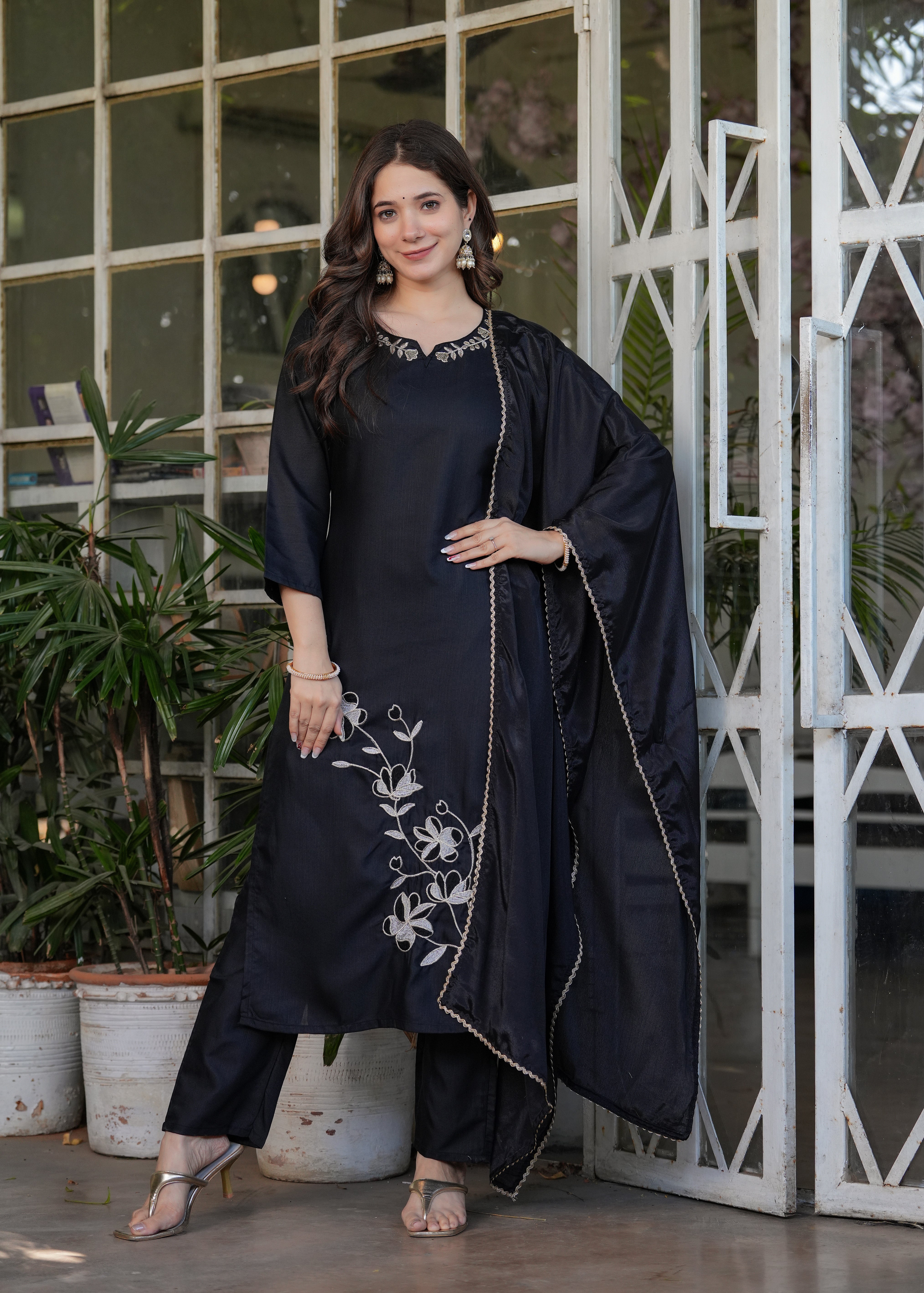 Confident woman posing in a stylish black kurta set with intricate white floral patterns, embodying TRENDBUY's elegance.