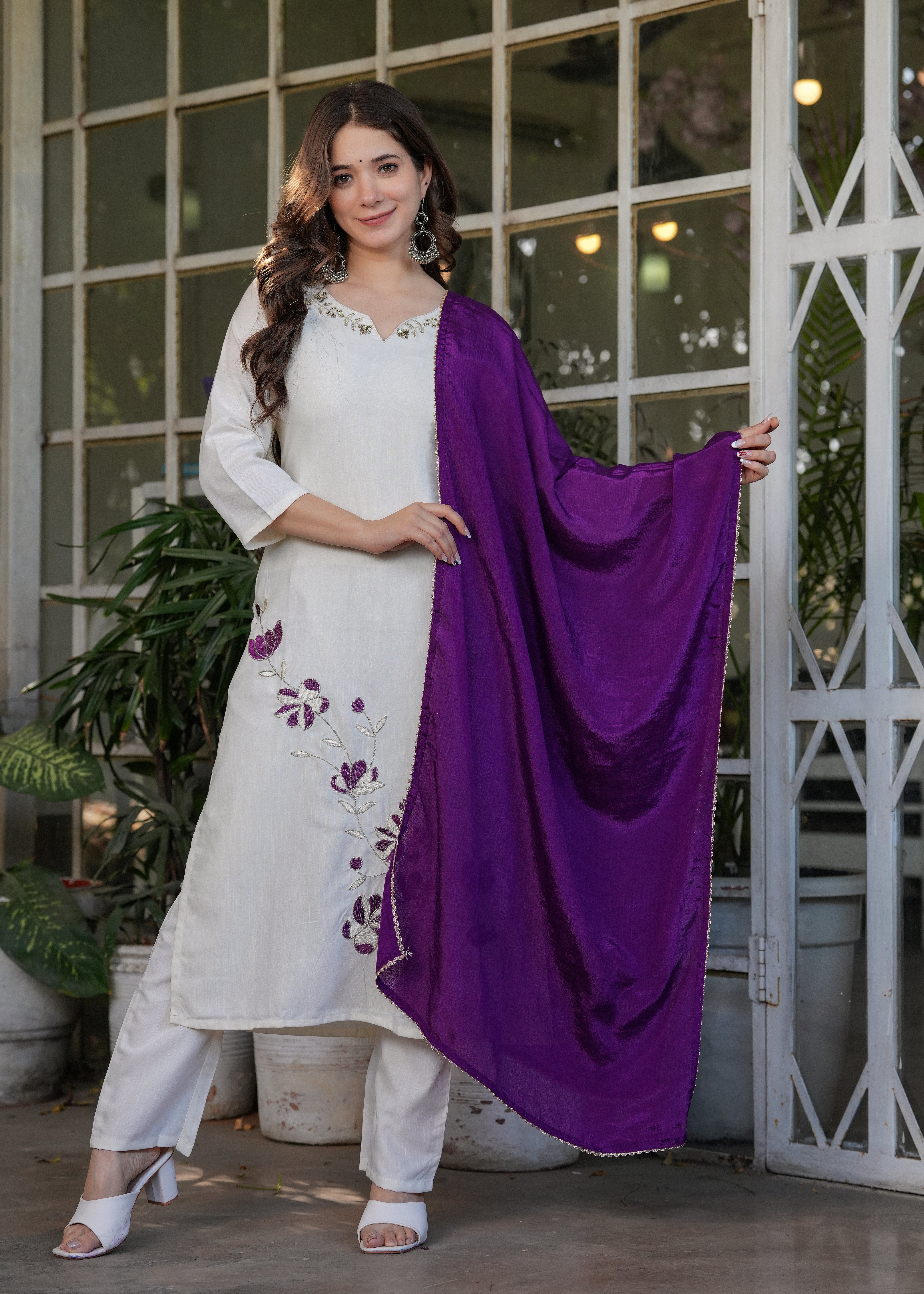 Woman in off-white embroidered kurta set with flowy purple dupatta, standing gracefully, a perfect TRENDBUY look.