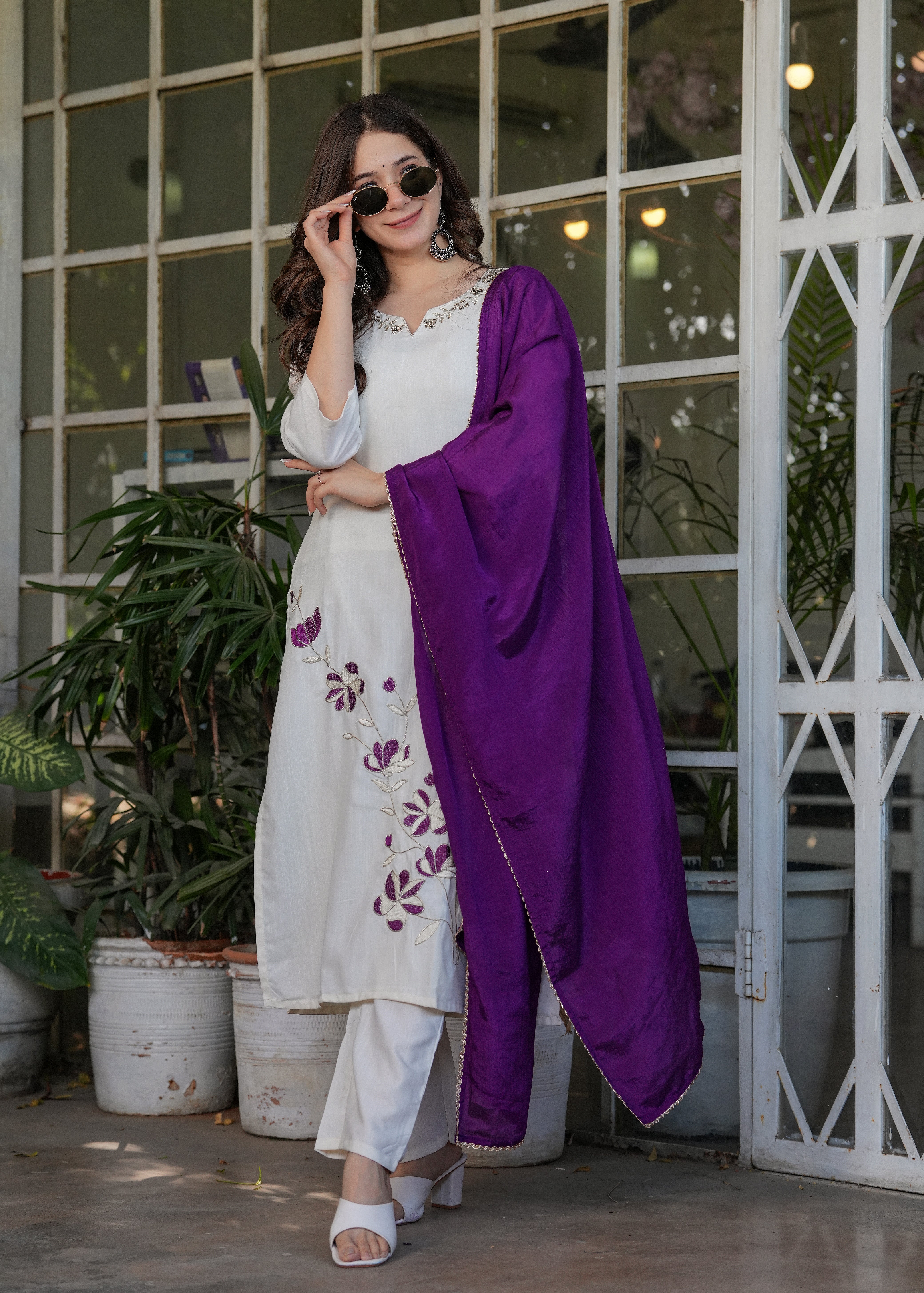 Model adjusting sunglasses while wearing an off-white embroidered kurta set with a striking purple dupatta from TRENDBUY.