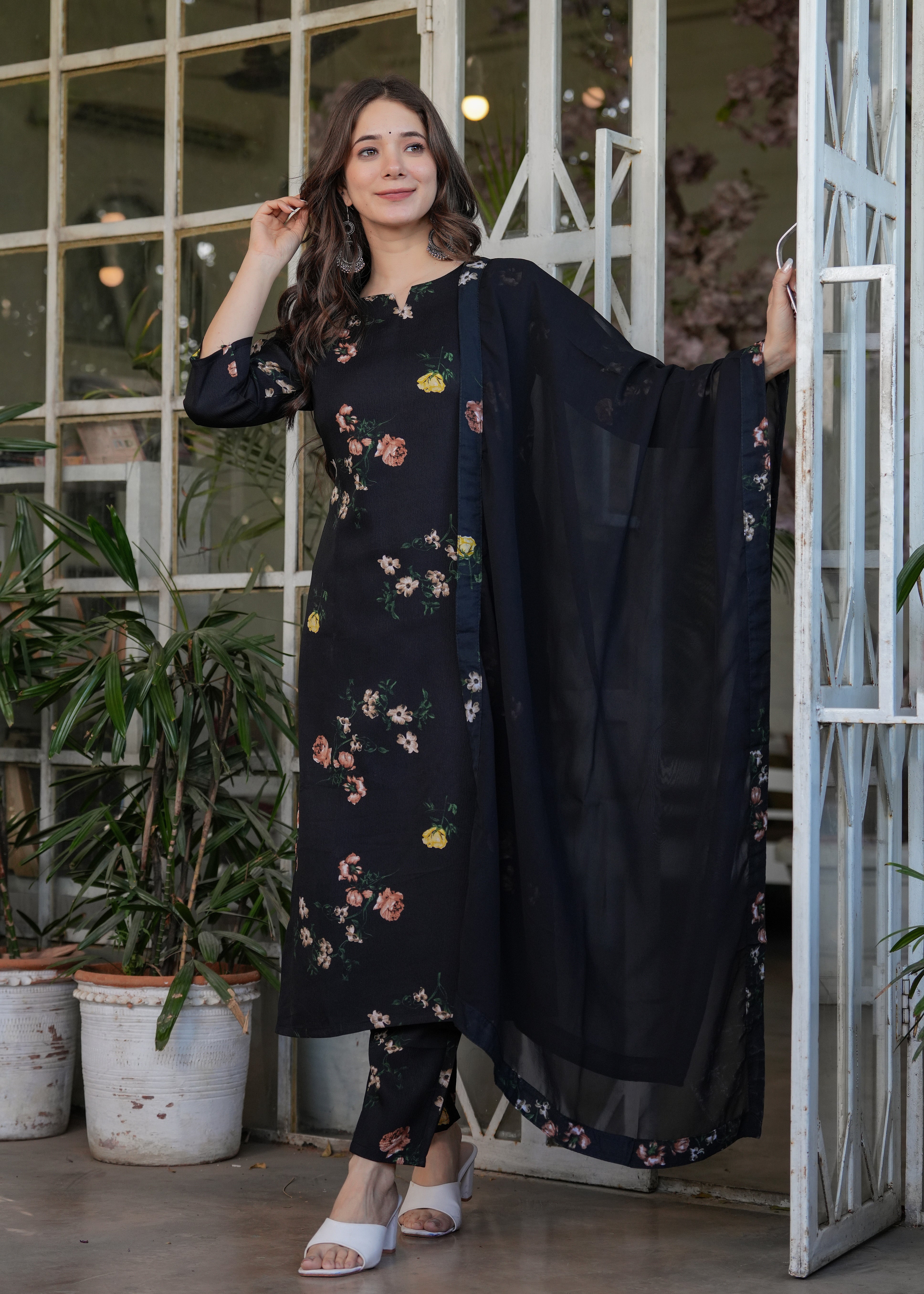Woman posing elegantly in a black silk blend printed straight kurti set with dupatta, showcasing the full outfit and intricate floral print.