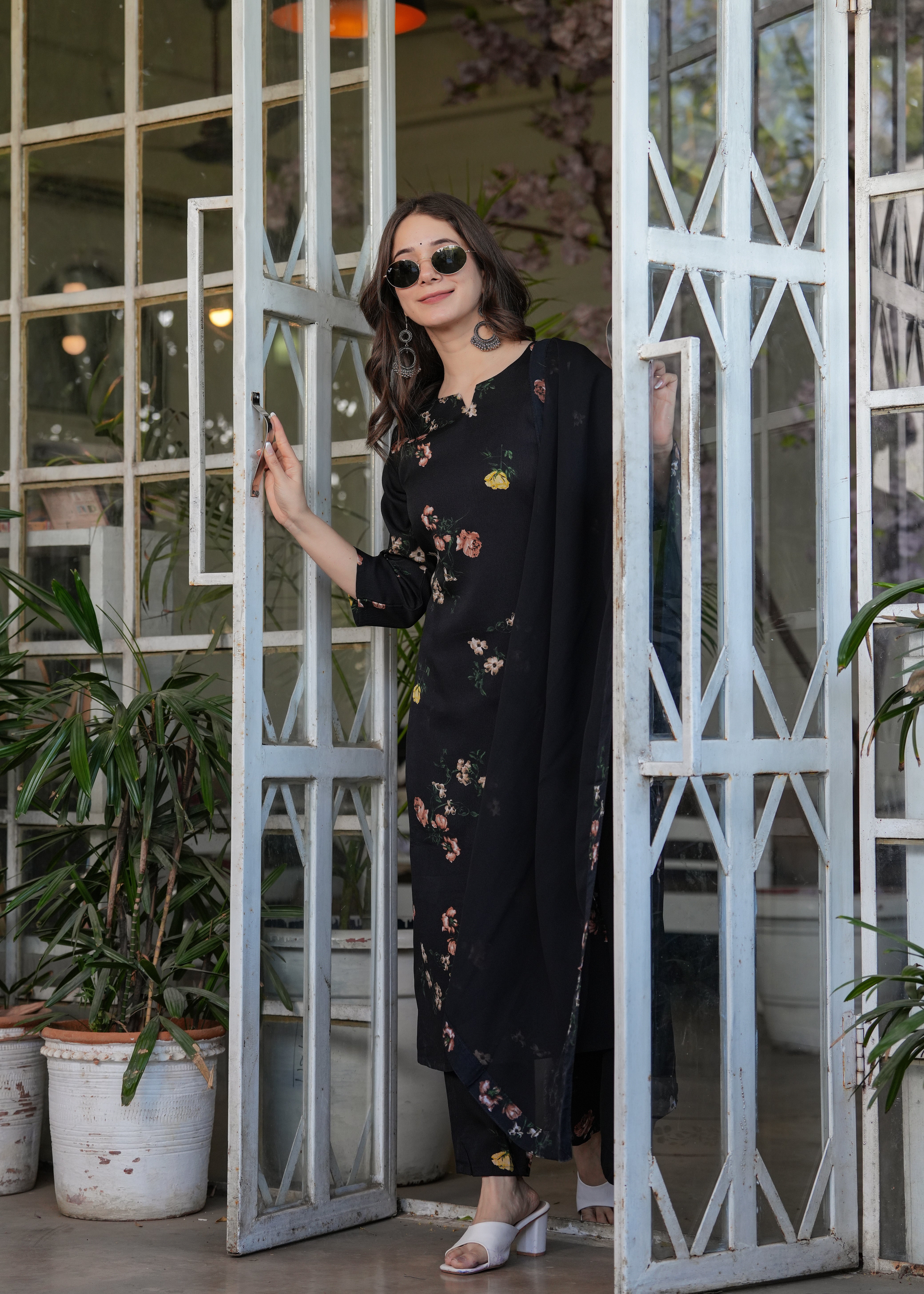 Fashionable woman wearing round sunglasses with the black silk blend printed kurti set, highlighting a modern ethnic look.