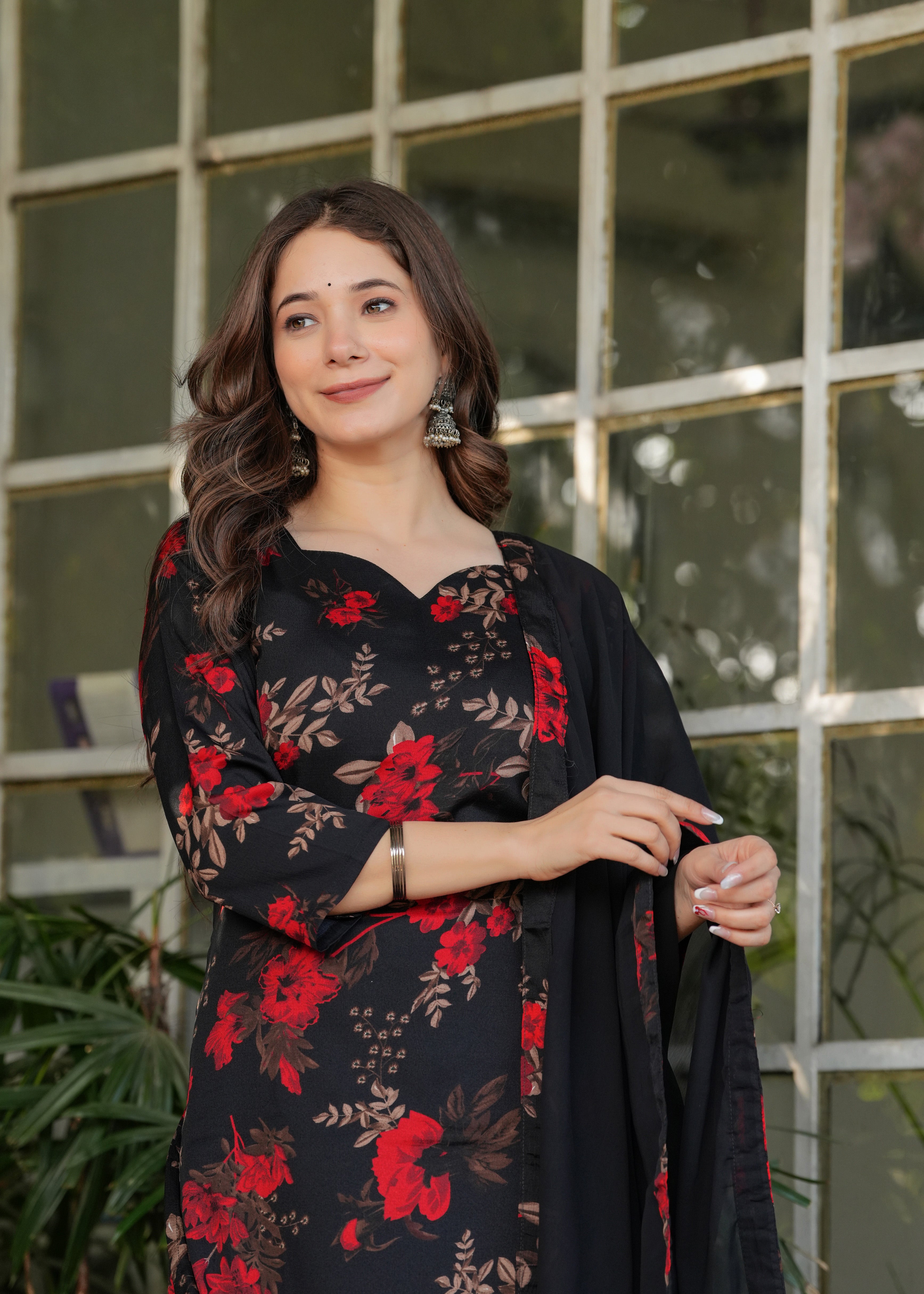 Close-up of woman's upper body in black floral print kurta, showcasing V-neckline and earrings.