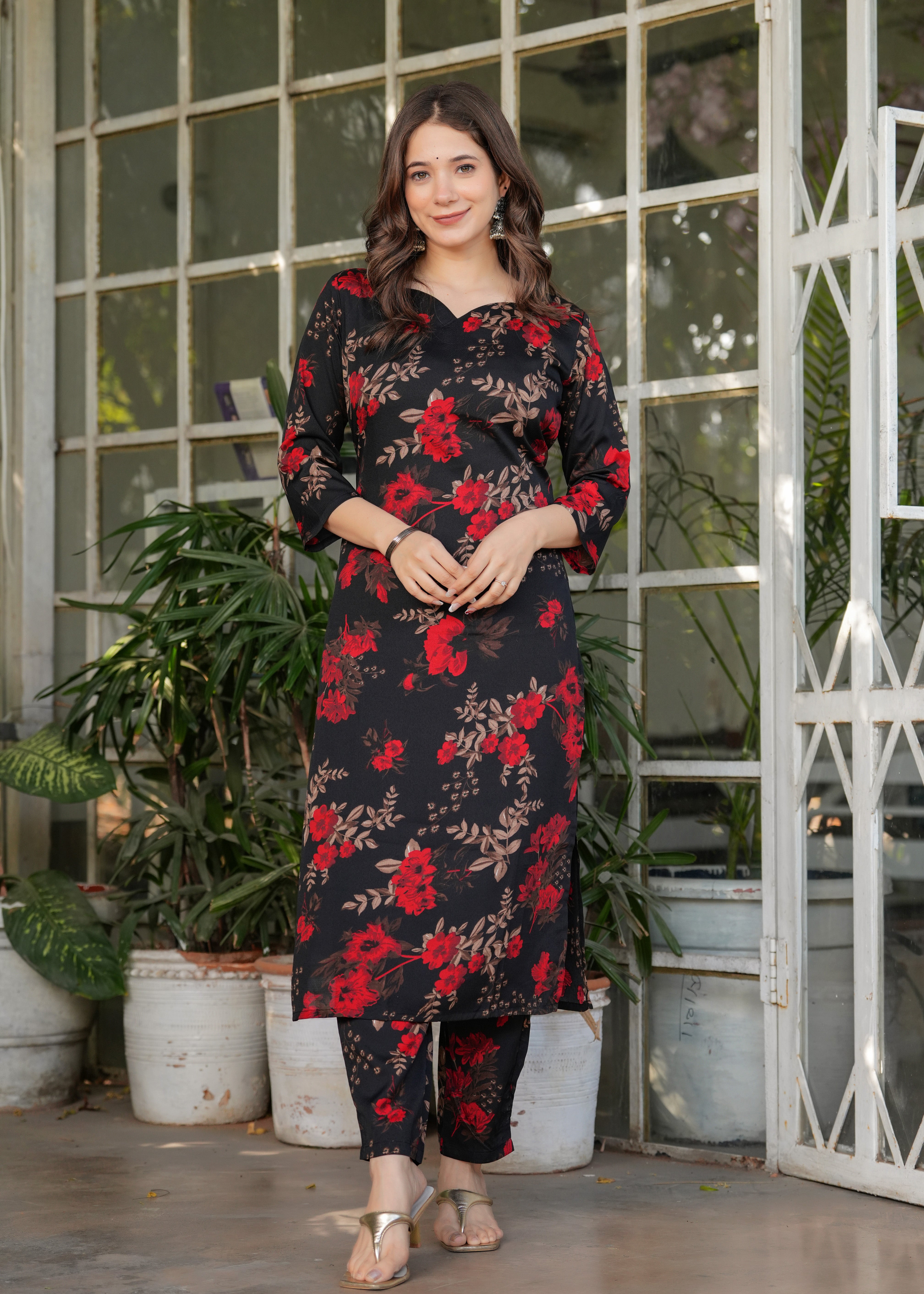 Front full-body shot of woman smiling in black silk blend printed kurta set with red flowers.