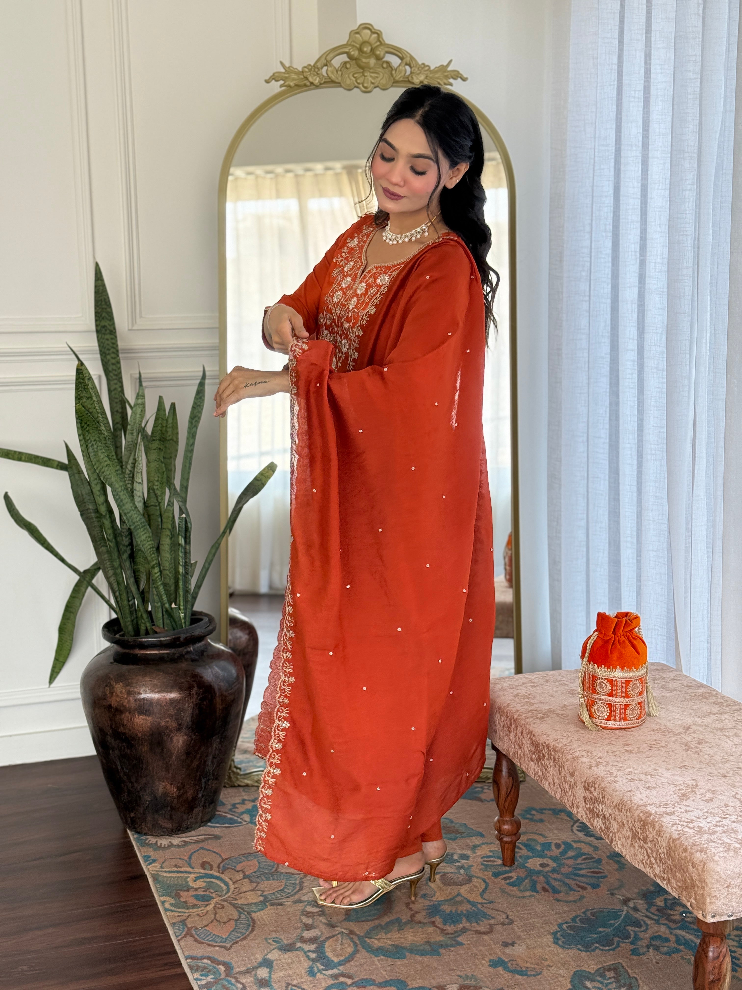 TRENDBUY model admiring the details of her sleeve, showing the cuff embroidery on the orange Viscose Chinon kurta set.