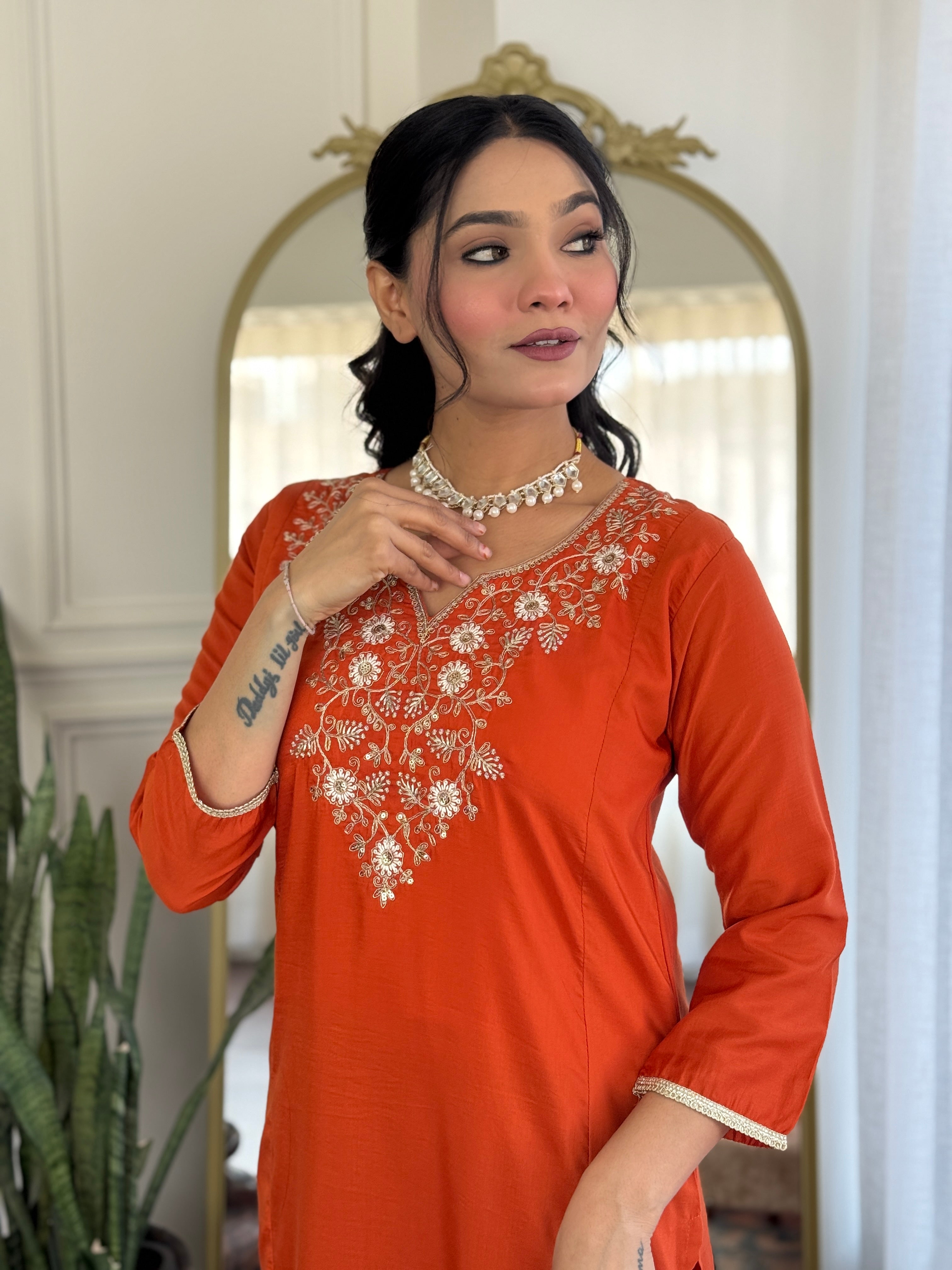 Close-up of the TRENDBUY model's face and embroidered neckline of the orange Viscose Chinon kurta, showing pearl necklace and delicate features.