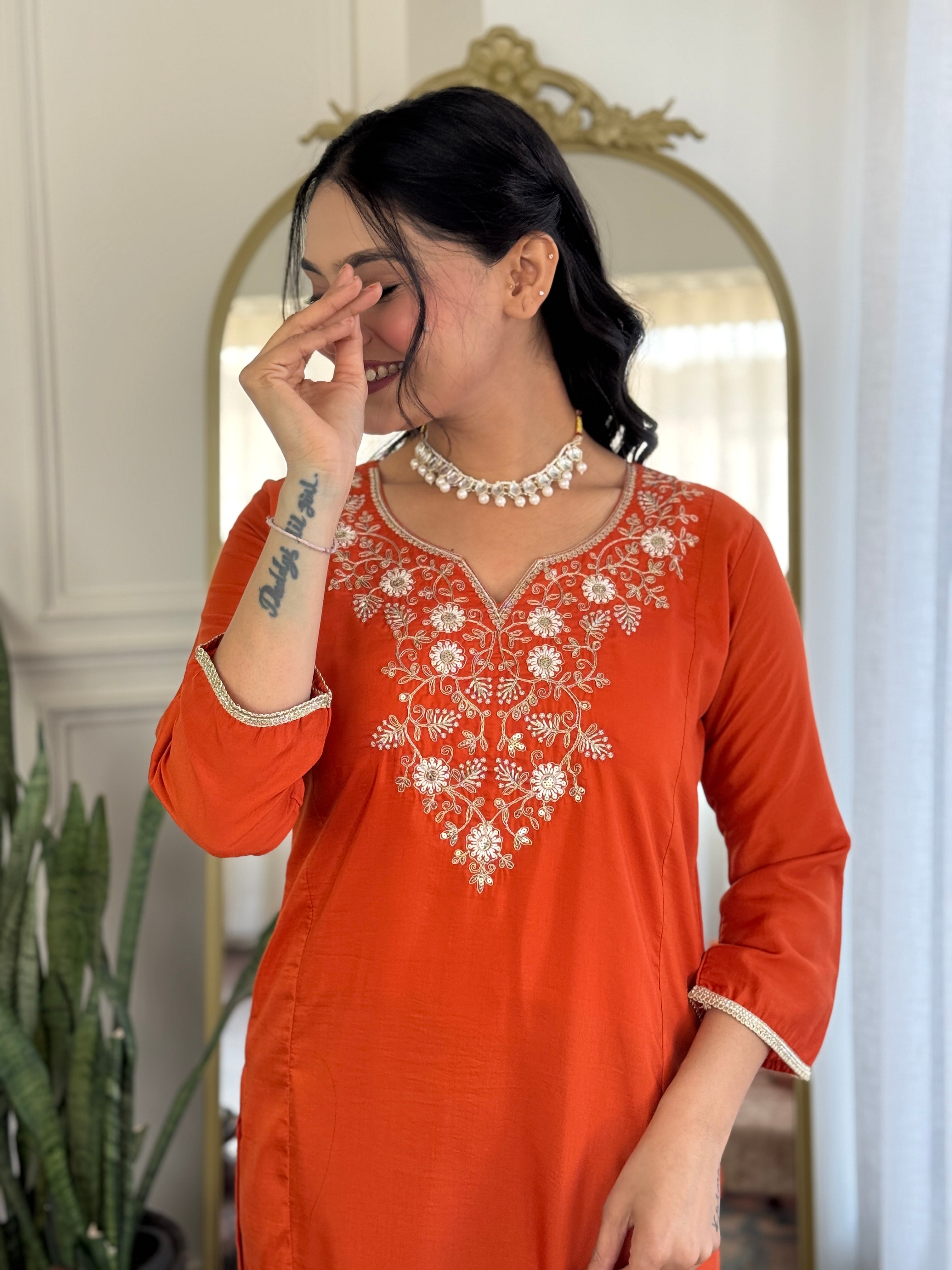 TRENDBUY model laughing with her hand near her face, highlighting the comfortable fabric and joyful appeal of the orange kurta set.