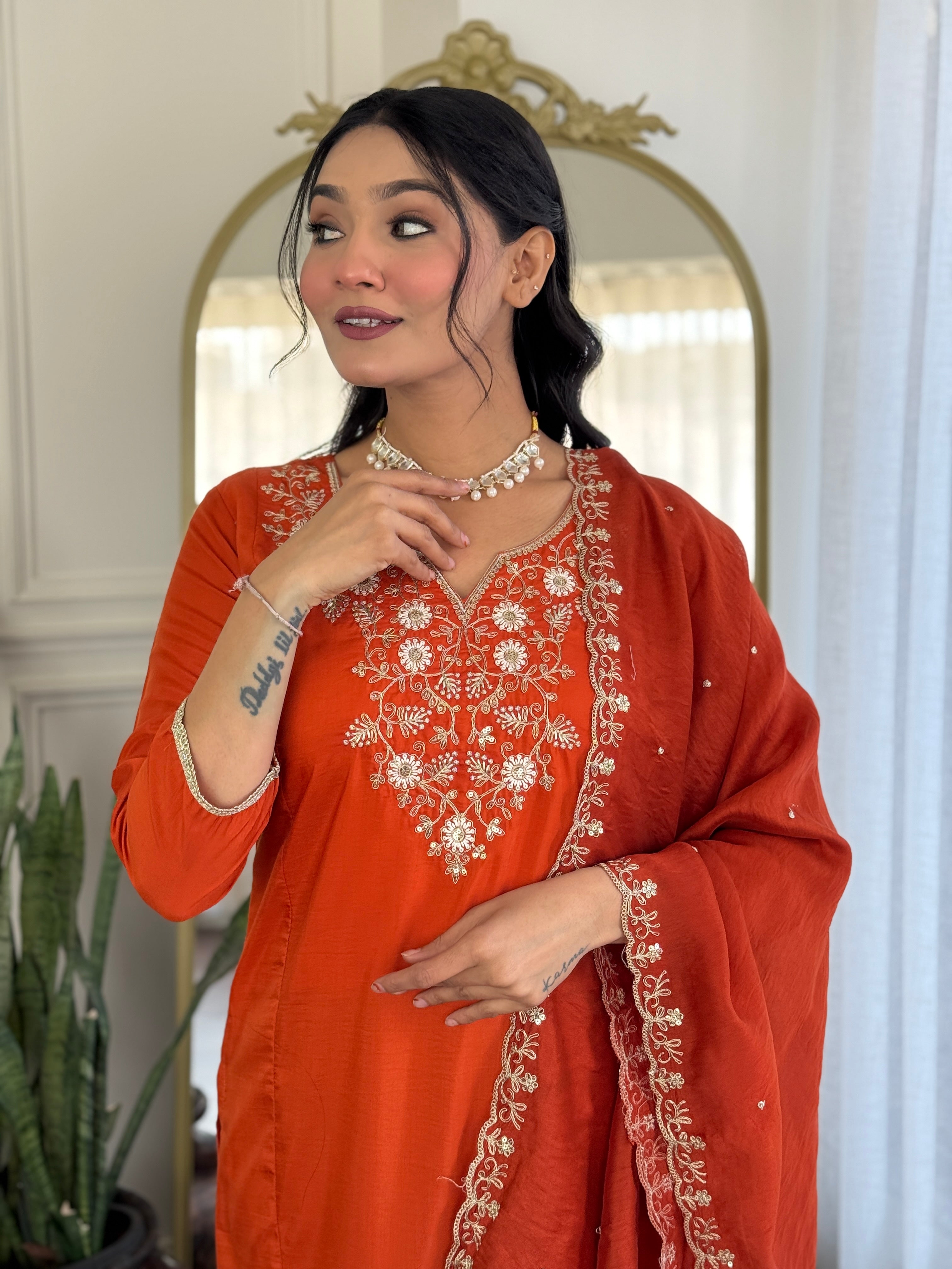 TRENDBUY model subtly adjusting her pearl necklace, showcasing the beautiful V-neck embroidery on the orange kurta.