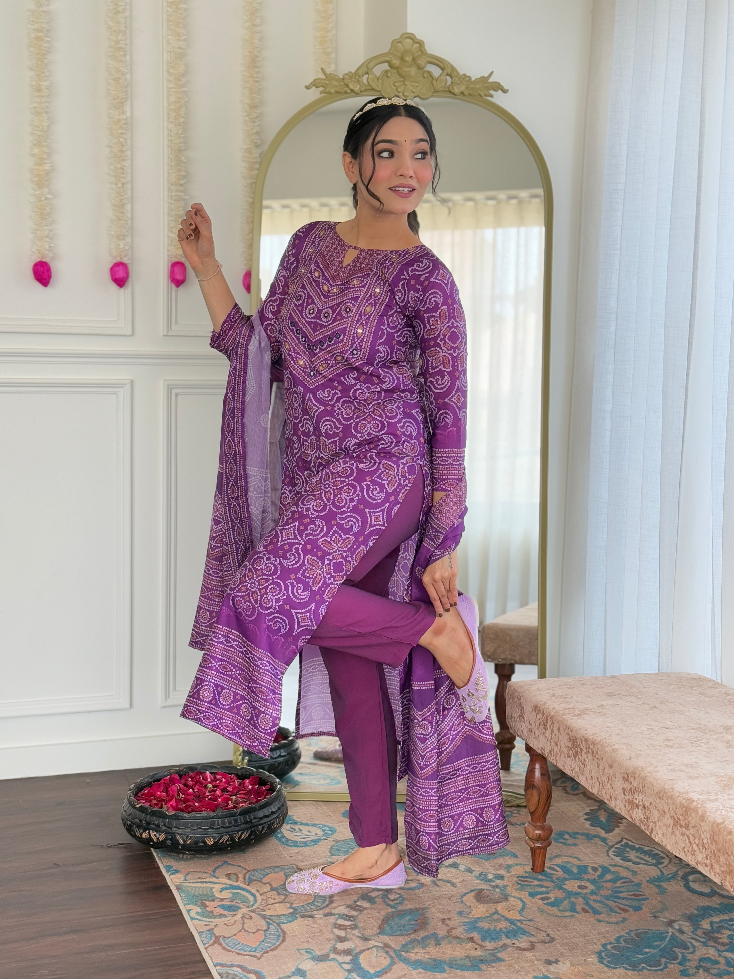 Model lifting a leg to show the comfortable fit of the viscose gadhval pants and the full purple kurti set.