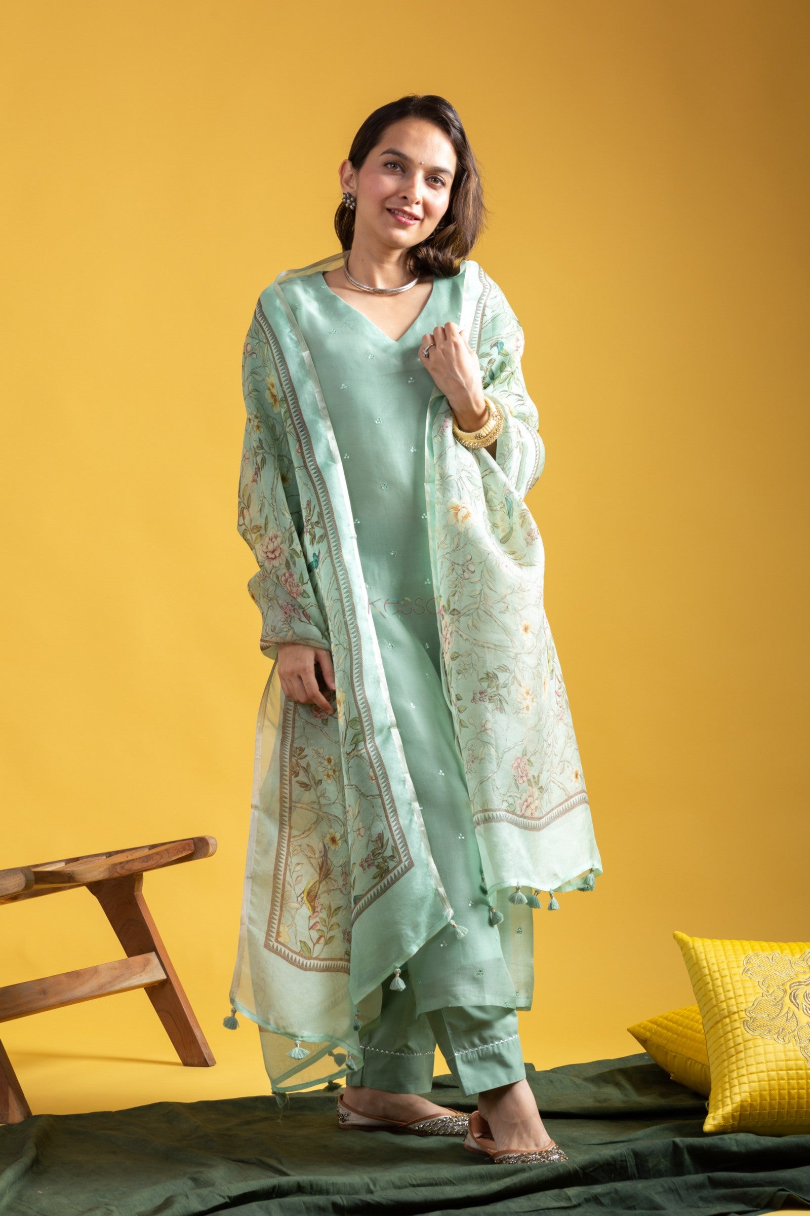 Full shot of woman in elegant mint green kurta set with floral patterned dupatta, smiling confidently.
