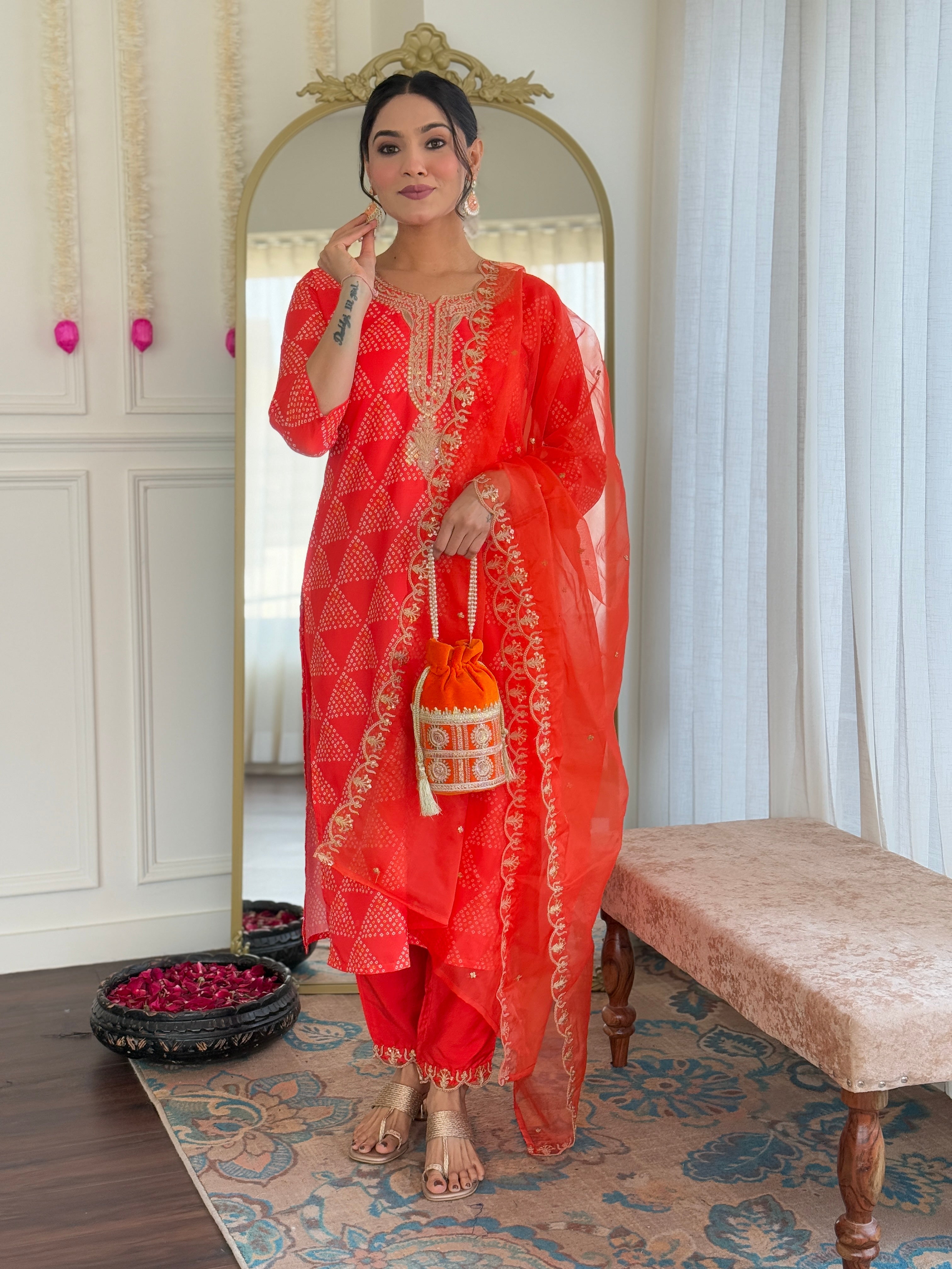 Full-length elegant pose of the woman in the MV-6025 orange kurti set, holding a matching embellished potli bag.