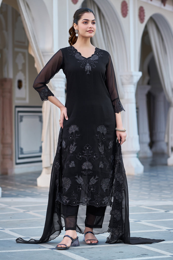 Full length view of a woman elegantly posing in a black embroidered georgette kurti, pant, and dupatta set, highlighting the outfit's flow and details.