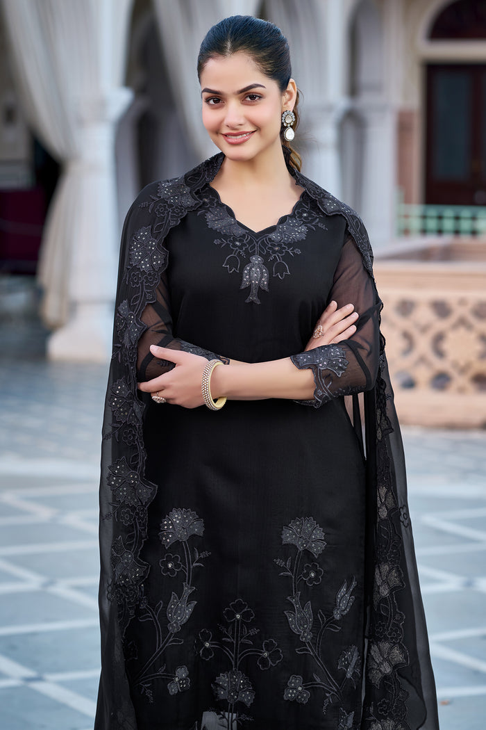 Close-up of the woman in the black kurti set, showcasing the detailed V-neck embroidery and sheer sleeves, with the embroidered dupatta draped over her shoulders.