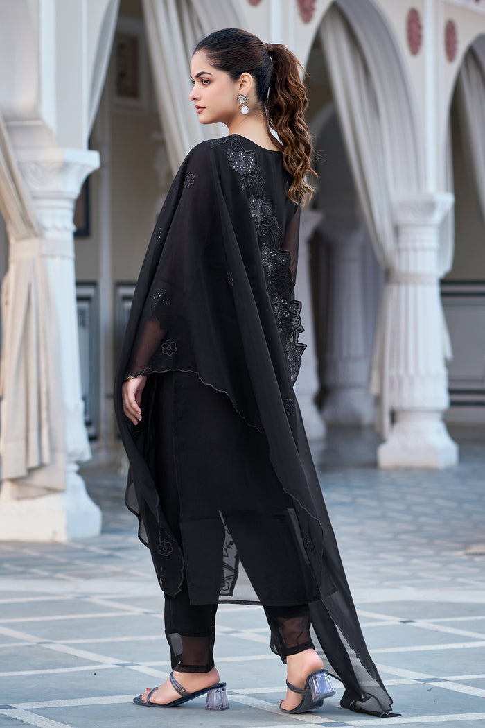 Back view of the black embroidered georgette kurti set, focusing on the sheer sleeves and dupatta's floral embroidery details as the model stands outdoors.