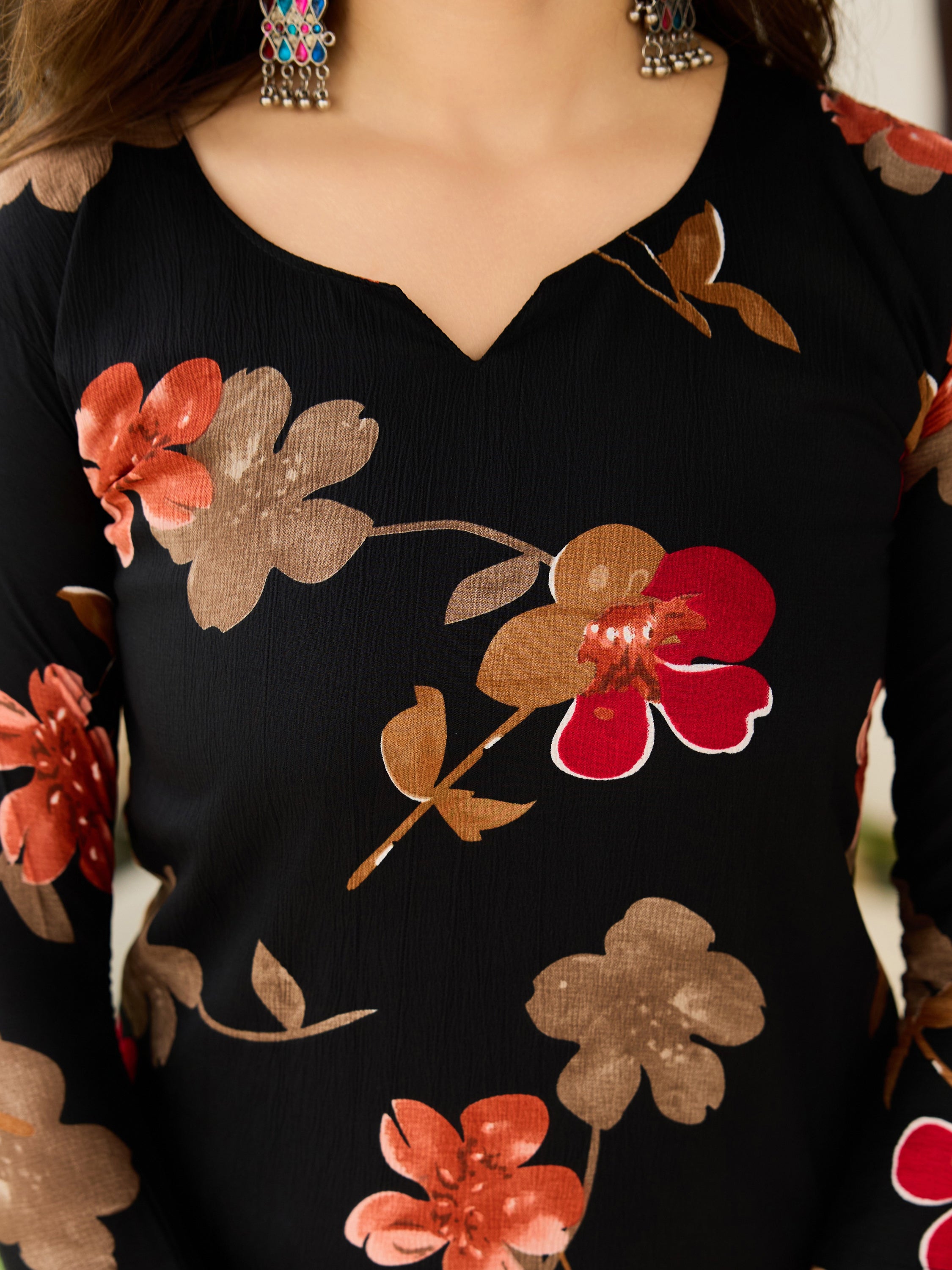 Detailed view of the black silk blend kurti fabric with vibrant red and brown floral embroidery design