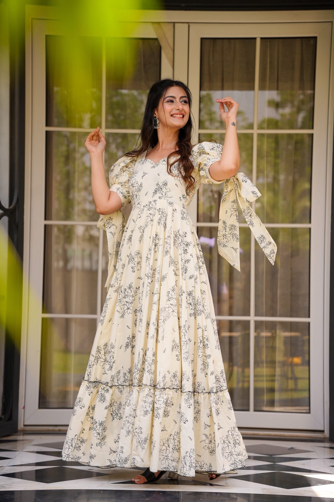 Smiling woman posing gracefully in a cream floral poly rayon maxi dress with puff tie sleeves, front view