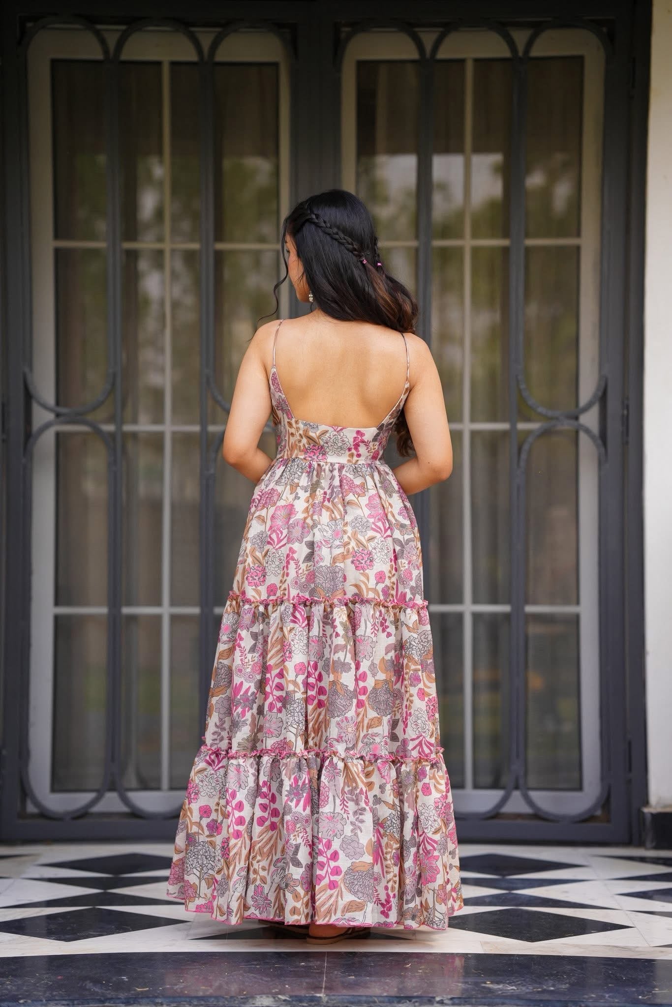 Back view of a woman showcasing the low-cut back and tiered skirt of the floral pattern Western maxi dress.