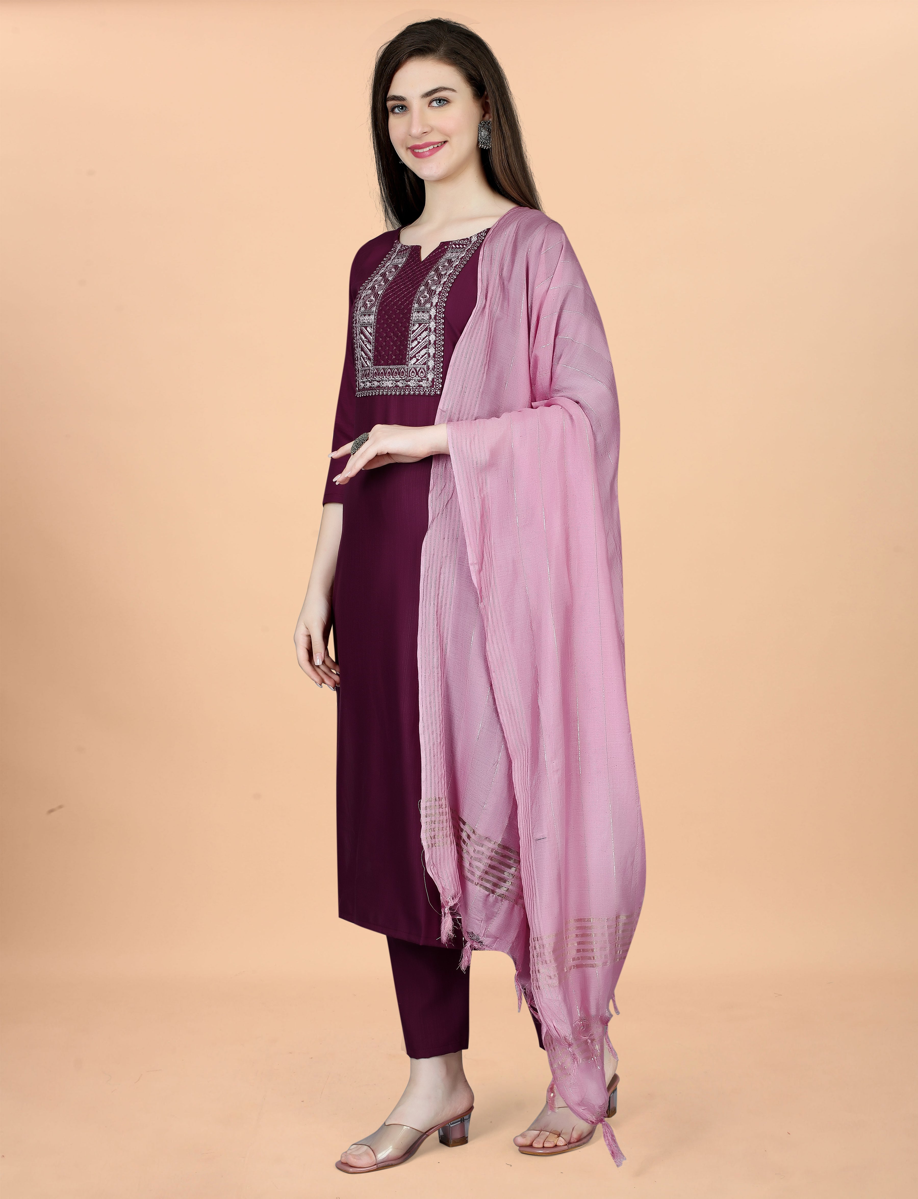 Side profile of a woman posing gracefully in a plum embroidered kurti set, highlighting the outfit's flow and details of the pink chanderi dupatta.