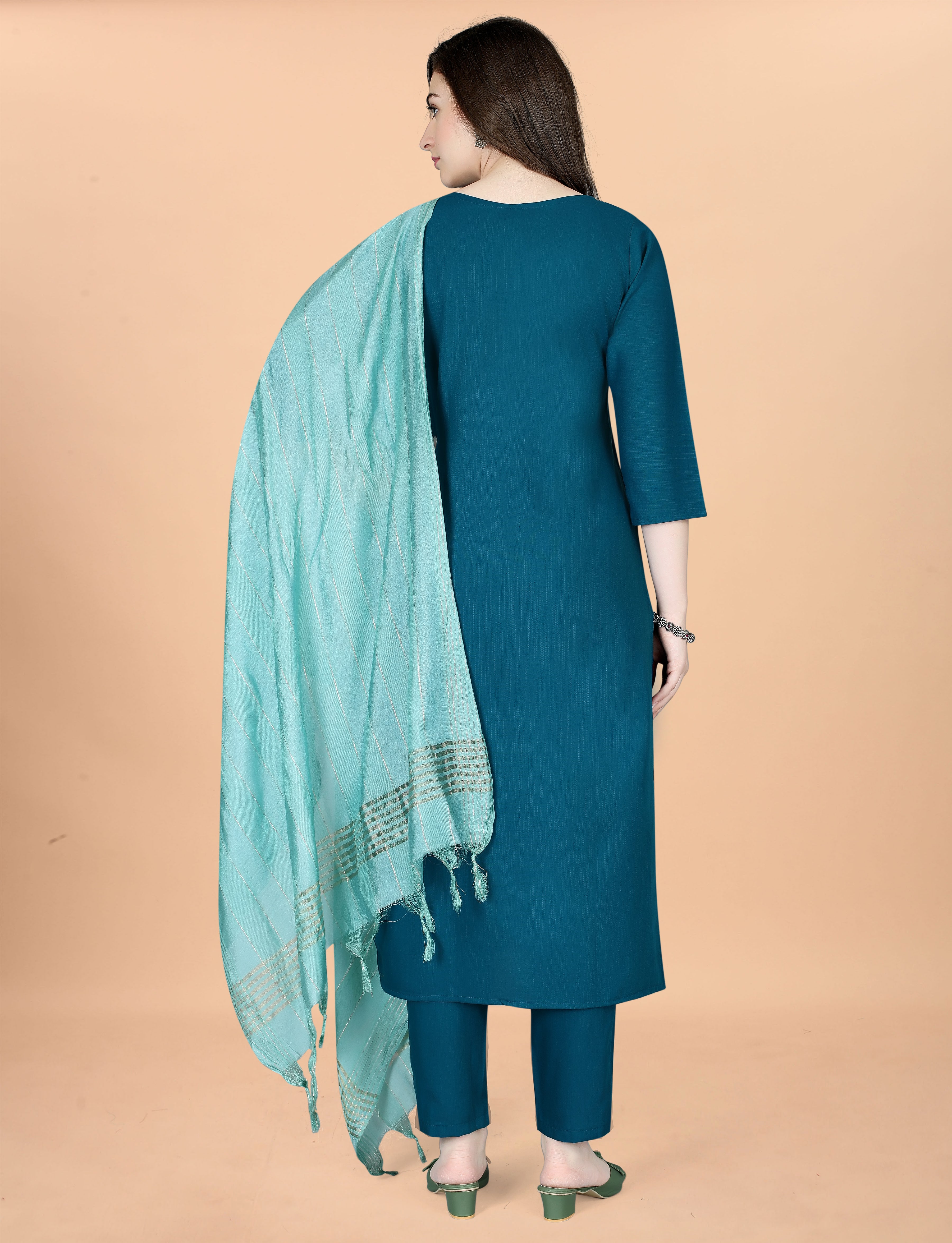 Back view of a woman wearing a teal embroidered cotton blend kurti, matching pant, and a light mint green chanderi dupatta.