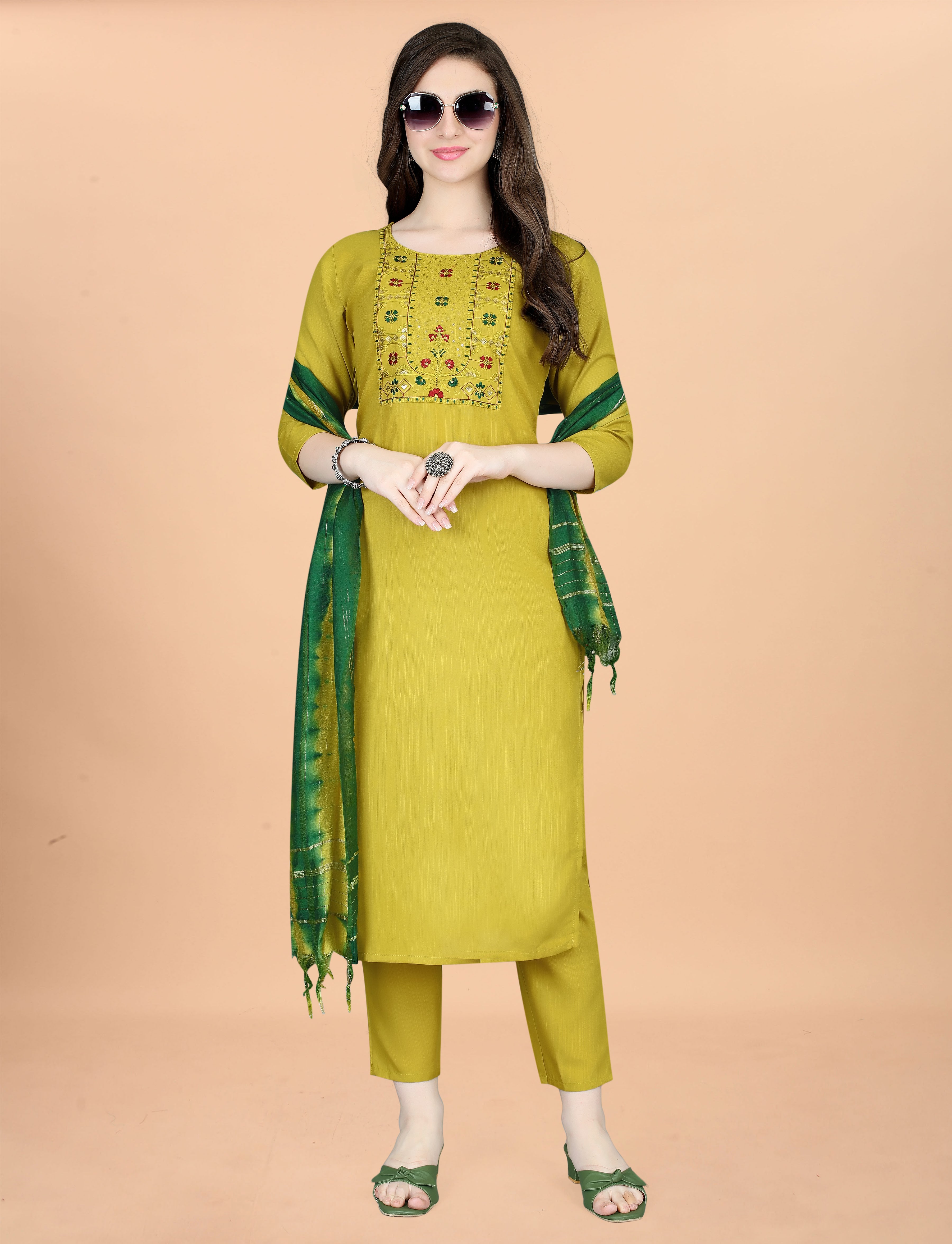Woman posing confidently in an olive green embroidered kurta set, sunglasses, and artistically draped tie-dye dupatta.