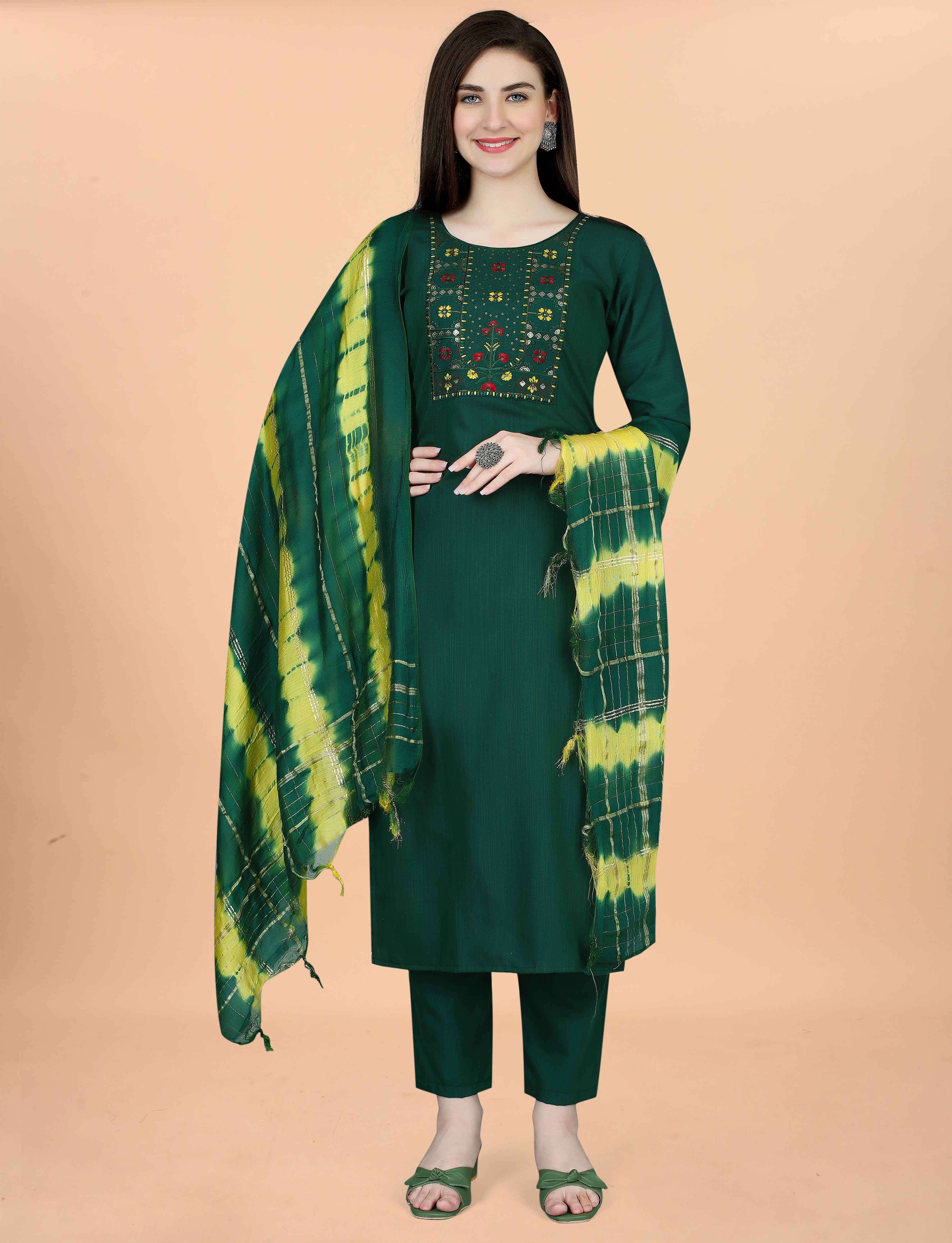 Full length shot of a woman elegantly posing in a deep green embroidered kurta set with a gracefully draped tie-dye dupatta.