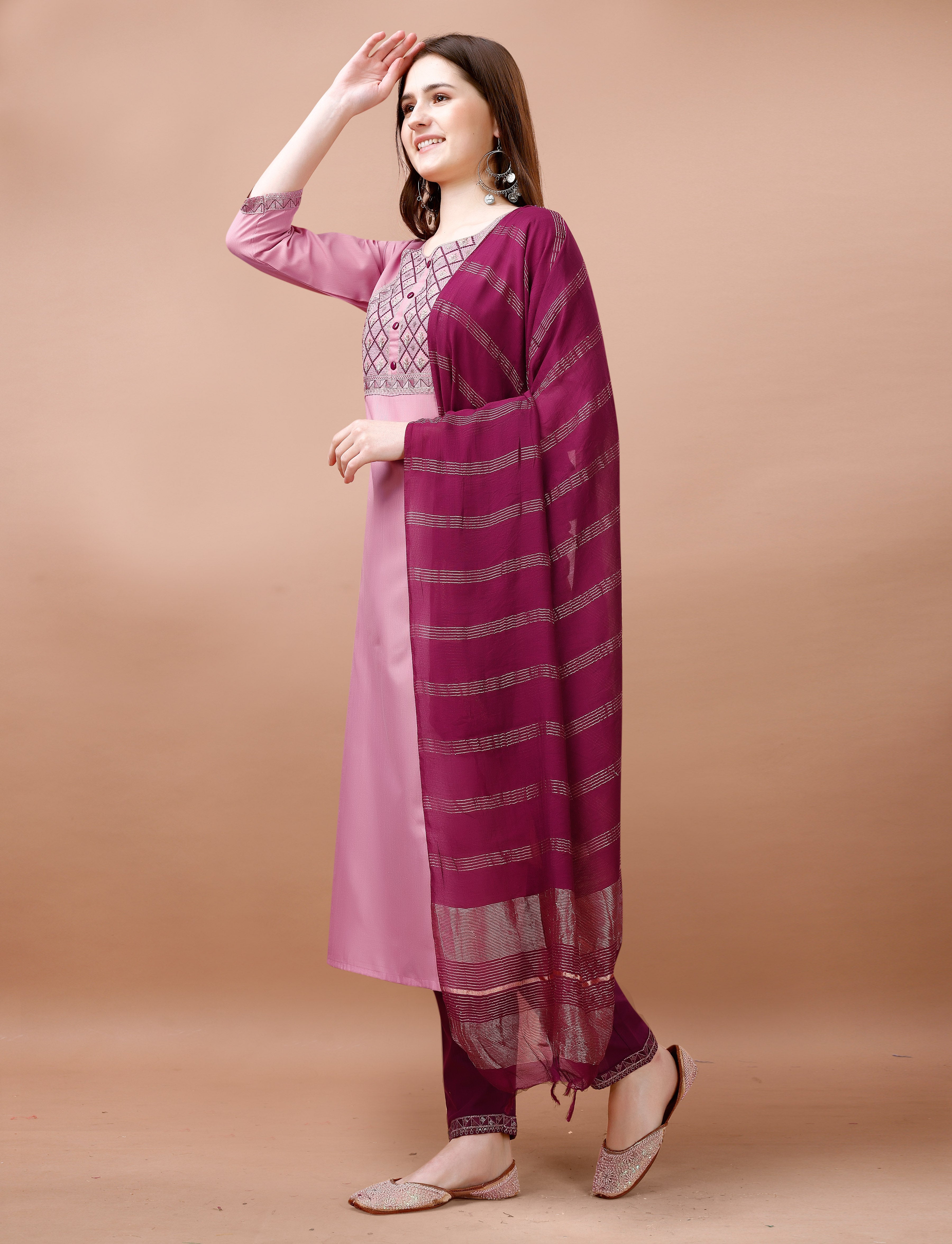 Woman posing gracefully in a blush pink embroidered kurta set, showing the full outfit with maroon dupatta and accessories.