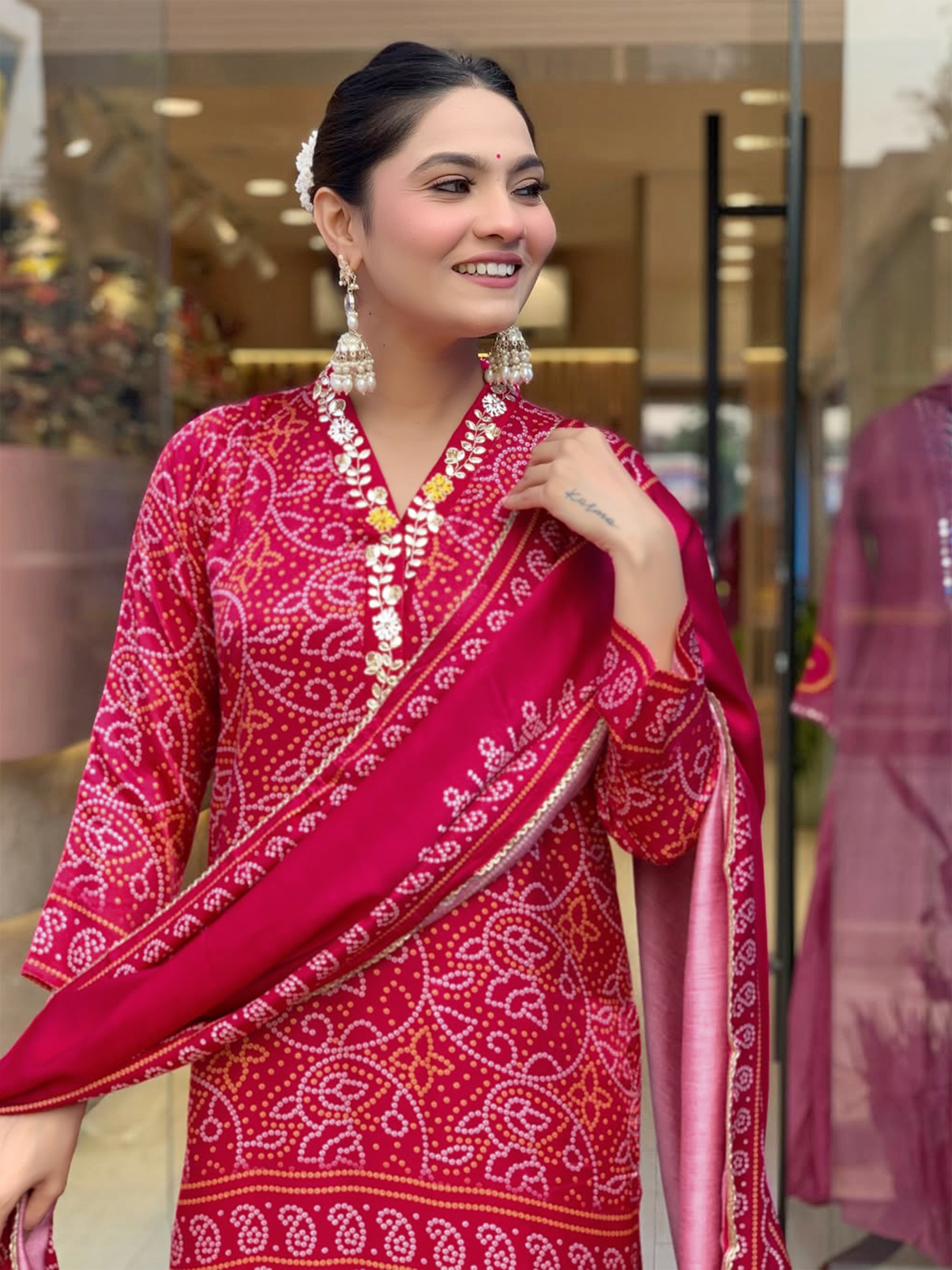 Close-up side profile of a woman smiling, showcasing the details of the hand-printed magenta Viscose Silk kurti and the elegant pearl earrings she is wearing.