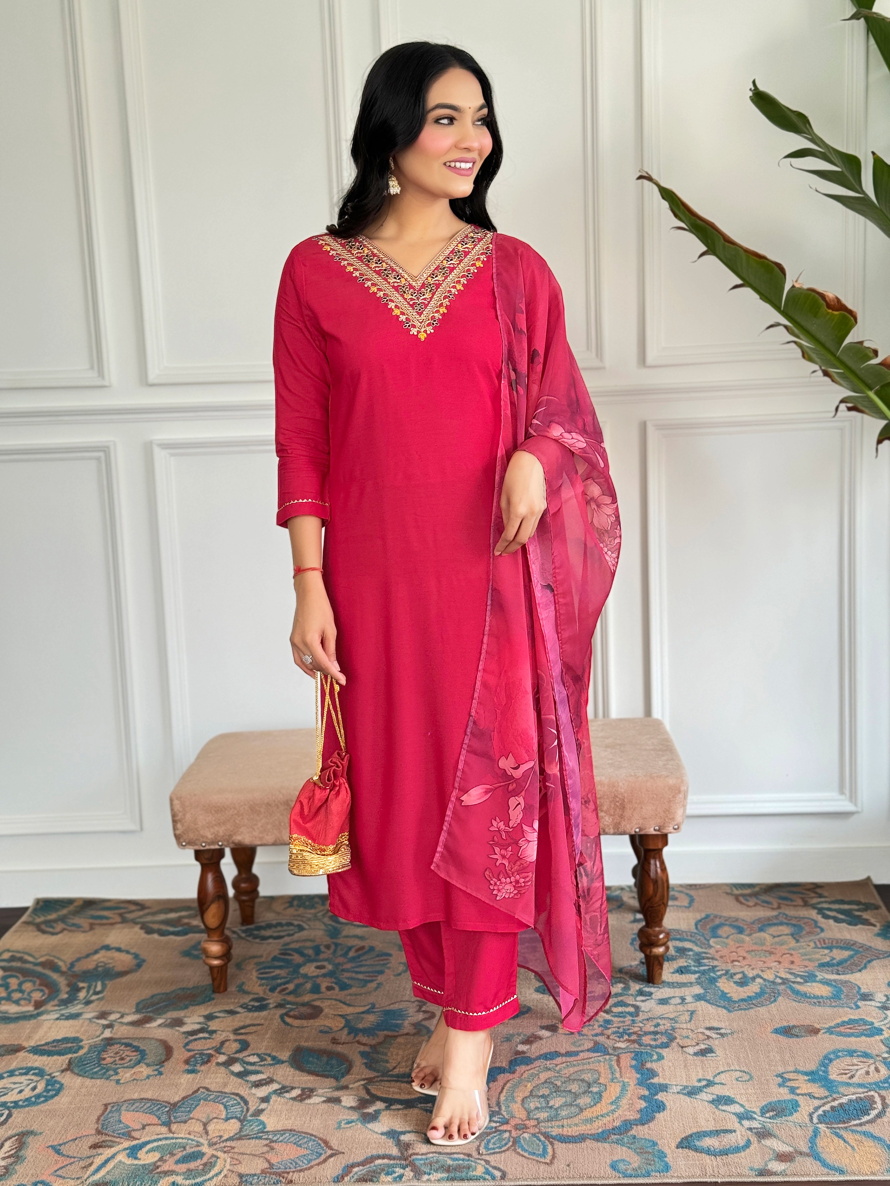 Model posing confidently in the TRENDBUY red rayon embroidered kurta set, holding a potli bag and smiling, embodying sophisticated ethnic style.