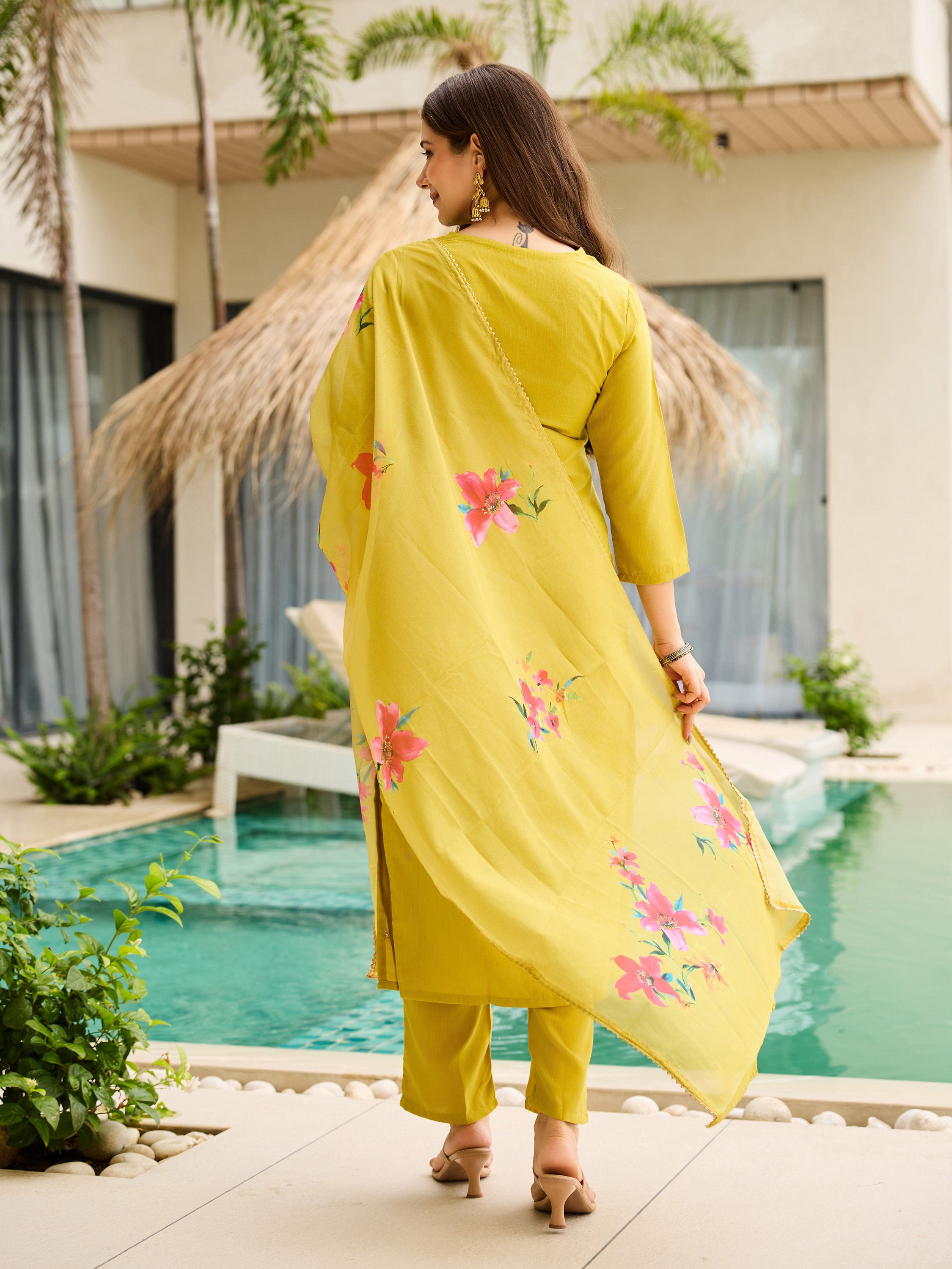 Back view of woman in a lemon yellow kurti set, showcasing the floral printed organza dupatta, near a pool.