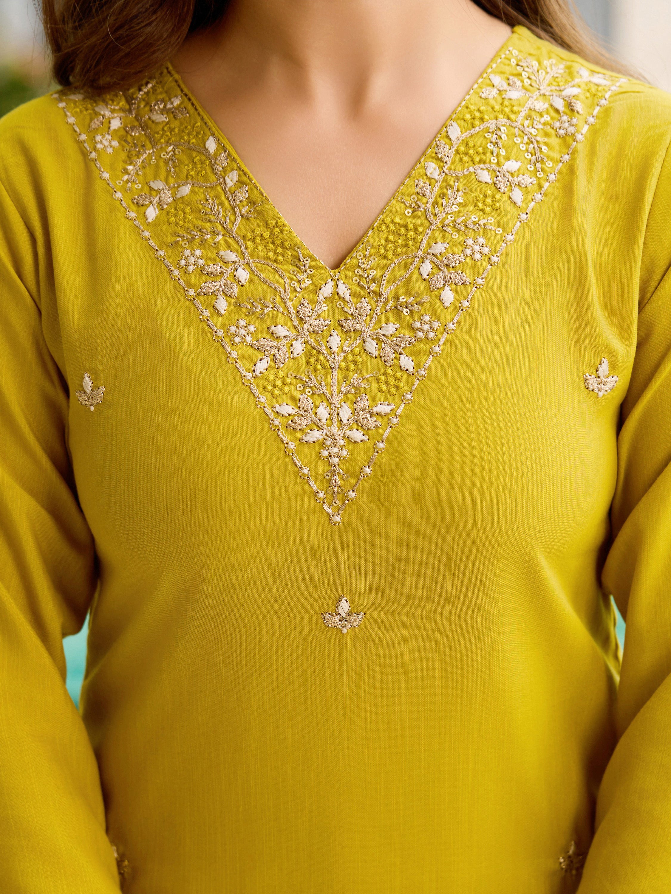 Close-up of the intricate white and gold embroidery on the V-neckline of the yellow rayon kurti.