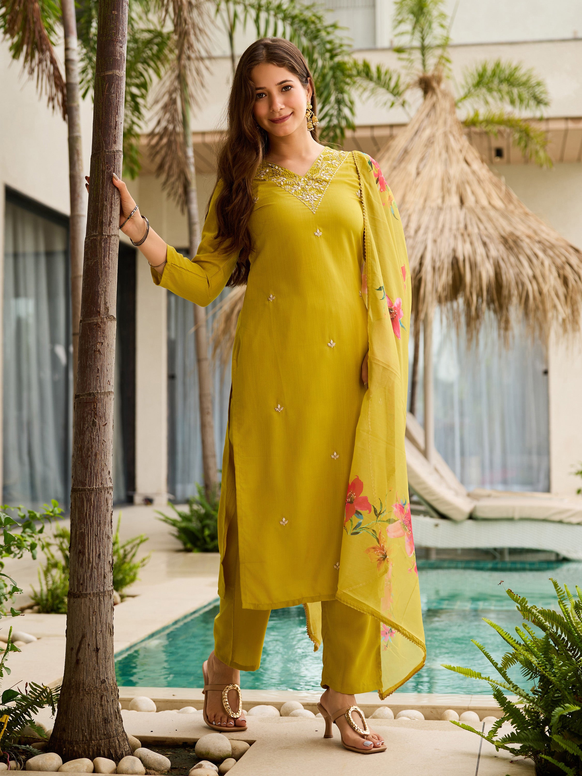Model elegantly posing by a palm tree, showcasing the full TRENDBUY yellow kurti set.
