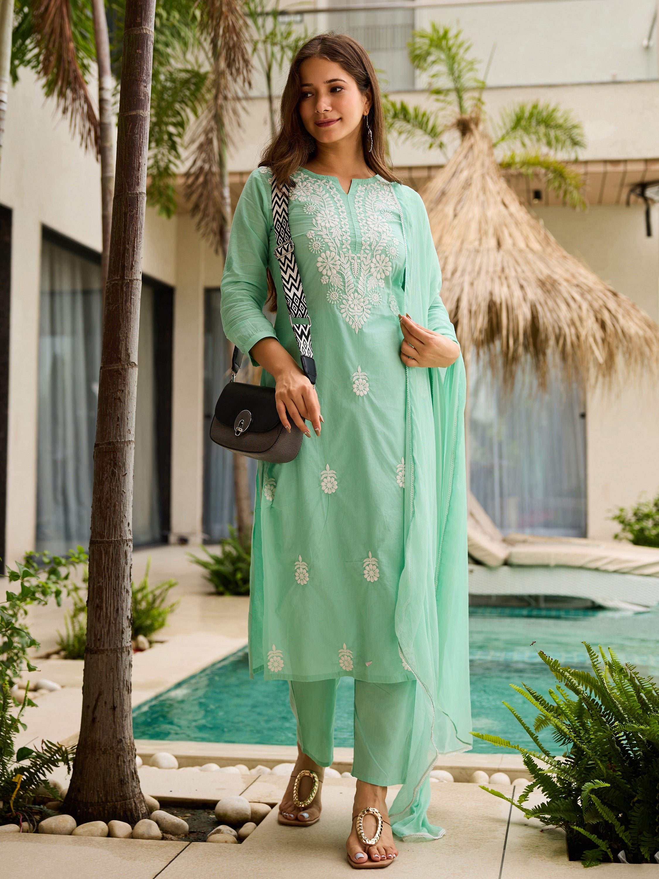 Model accessorized with a black handbag, showcasing the versatility of the turquoise embroidered kurti set.