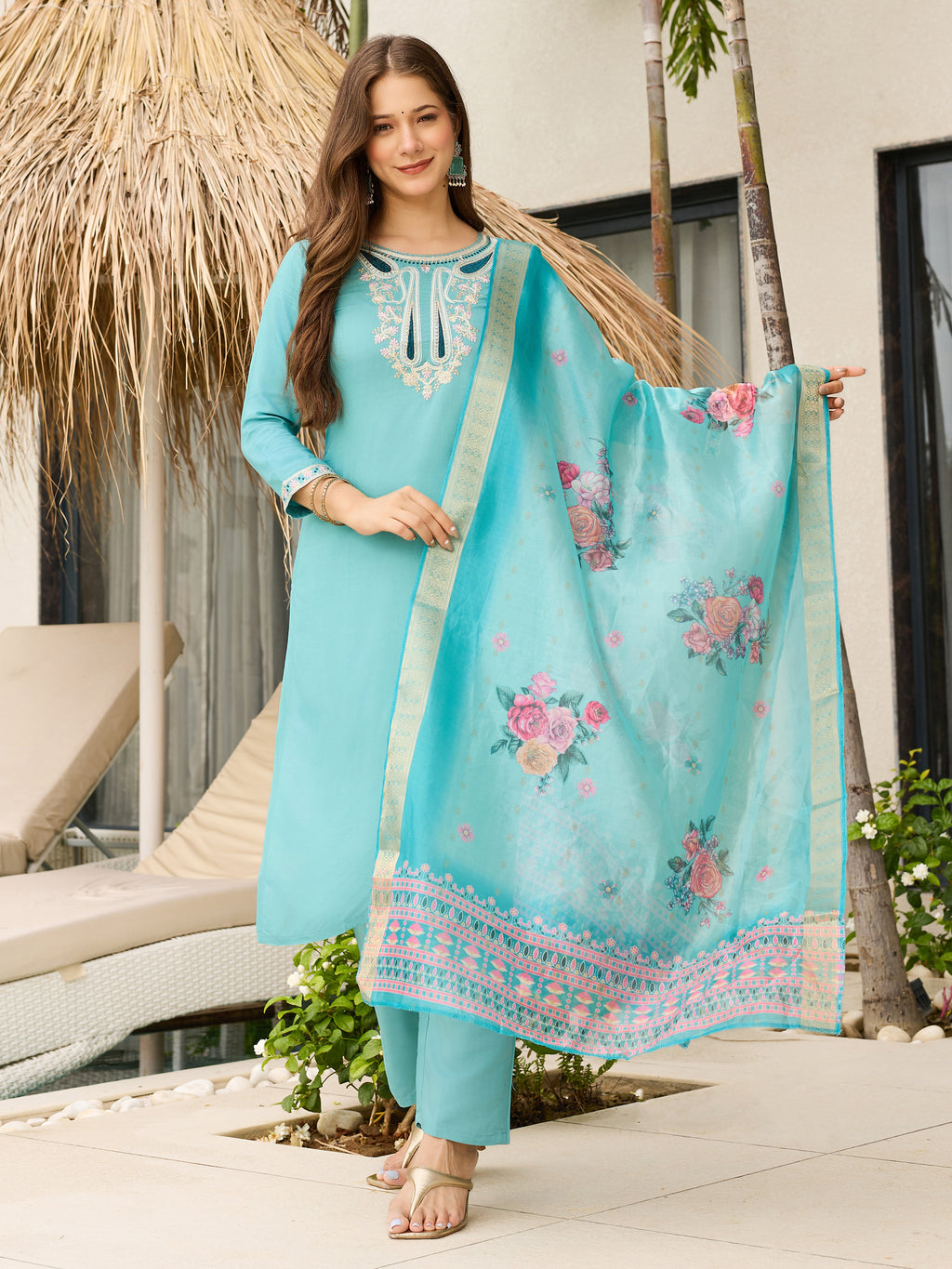 Full shot of a model wearing a teal blue viscose embroidered kurti set with an organza floral dupatta, standing outdoors.