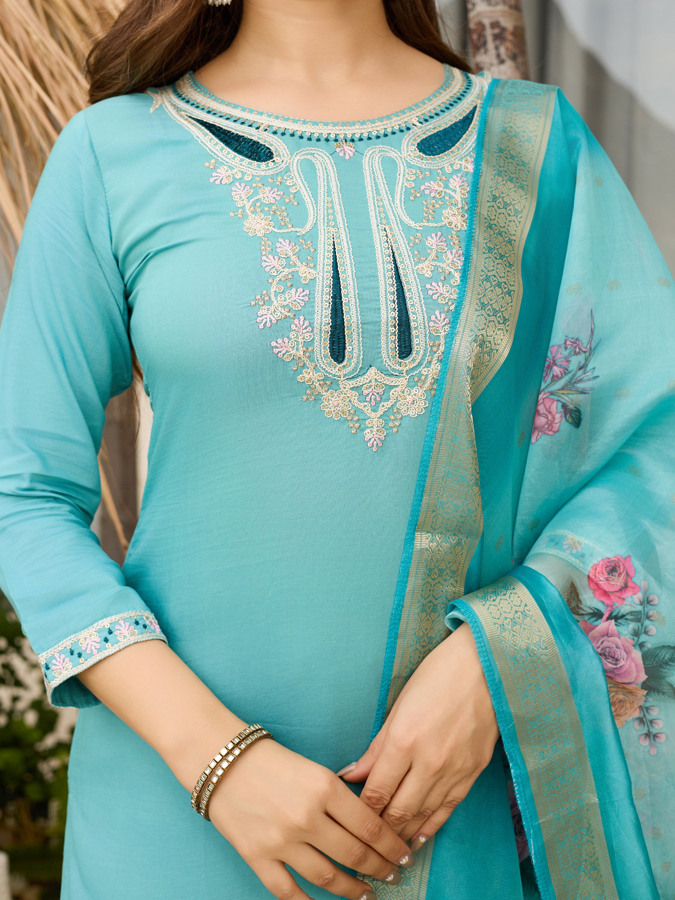 Close-up detail of the intricate white and pink embroidery on the teal blue viscose kurti neckline and the floral pattern on the organza dupatta.