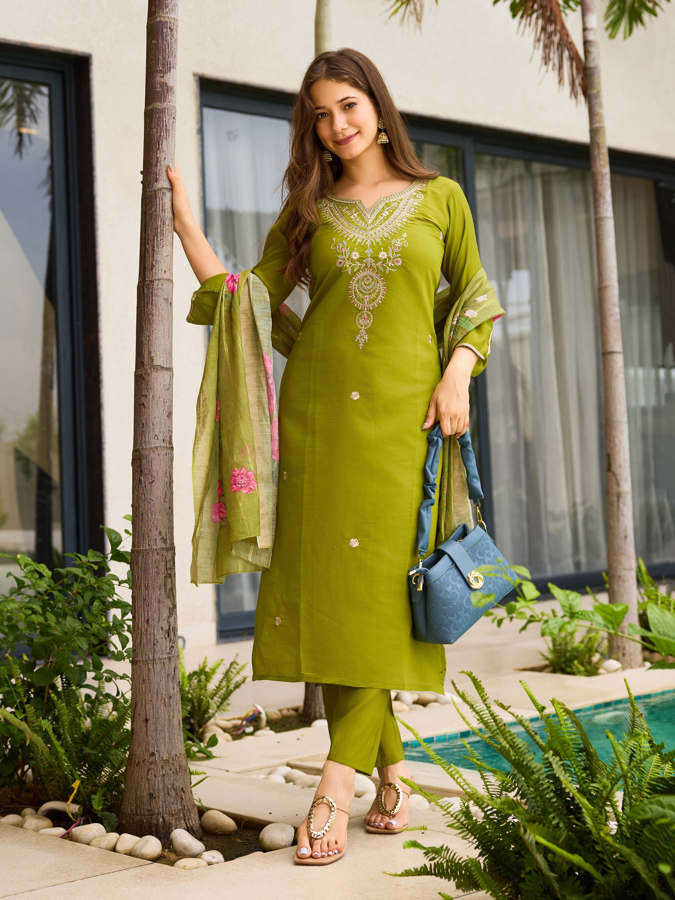 TRENDBUY model standing beside a palm tree, holding a handbag, wearing a stylish lime green kurti pant and dupatta set