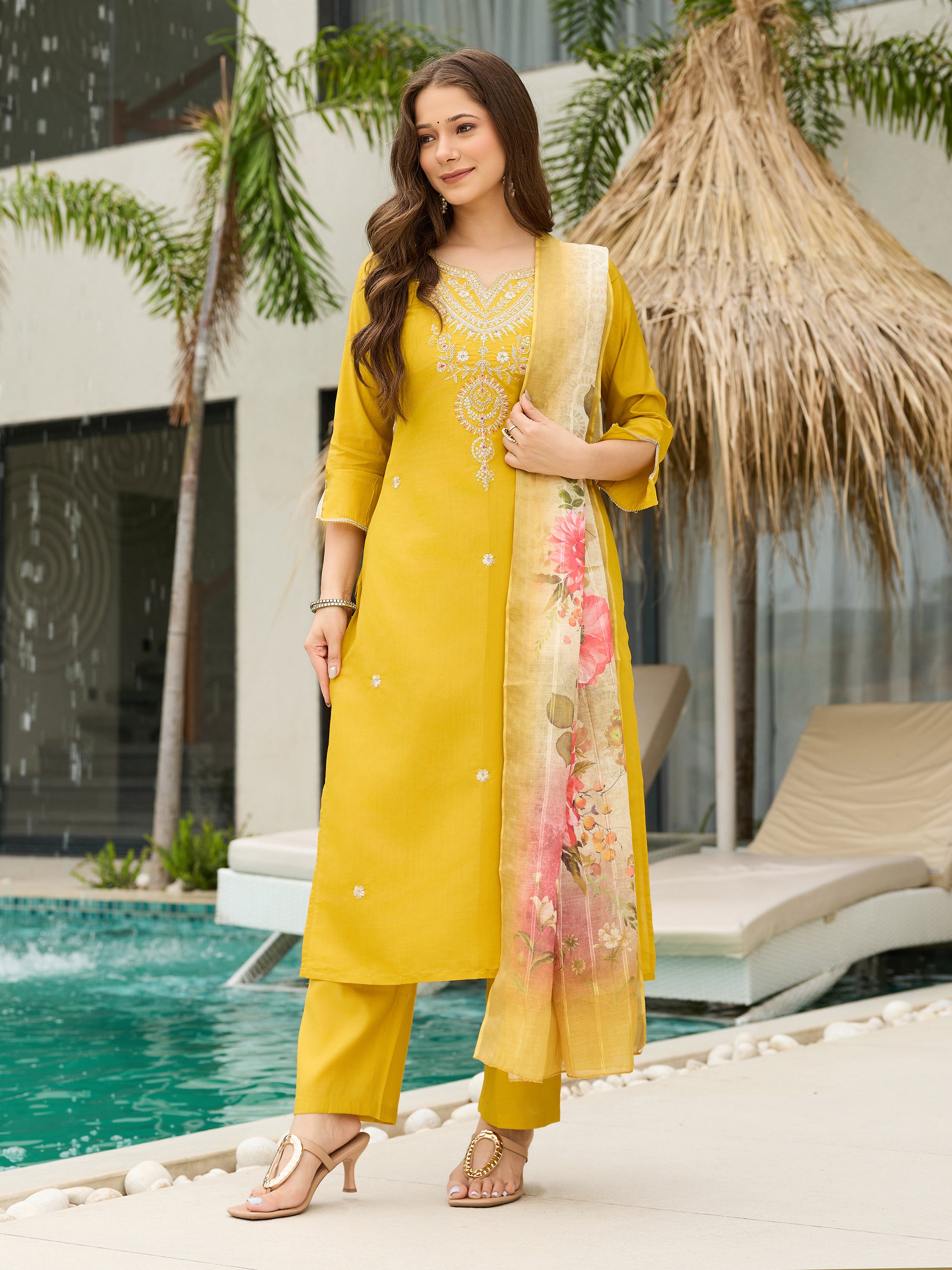 TRENDBUY model gracefully posing in a mustard yellow embroidered kurti set, dupatta draped, next to a swimming pool