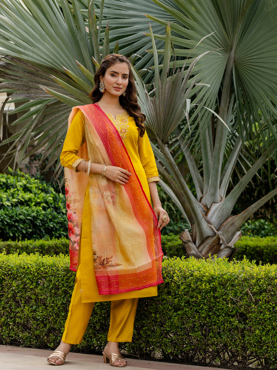 Outdoor full shot of the mustard ethnic wear, featuring the elegant drape of the embroidered kurti and floral dupatta in a garden setting