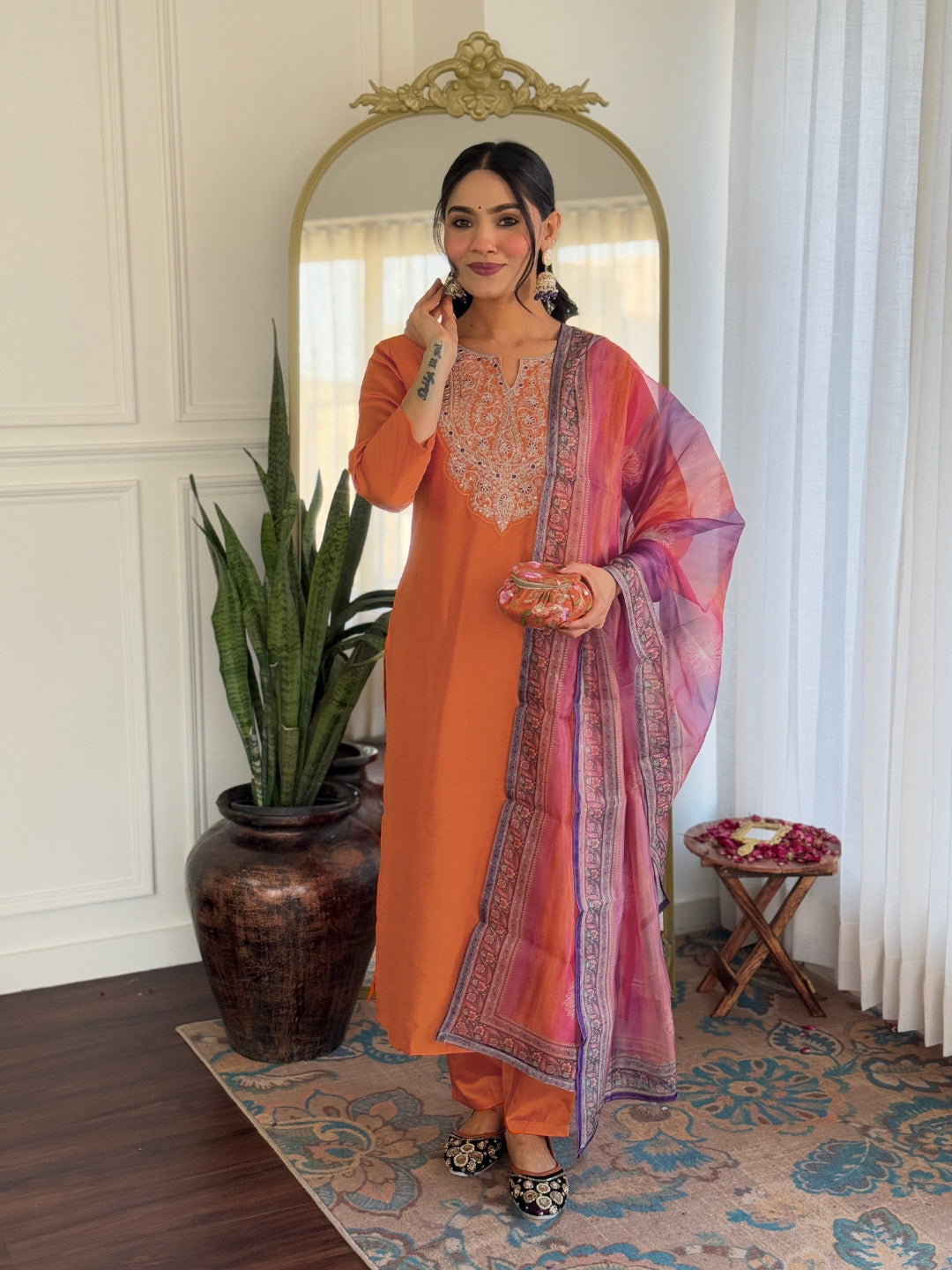 Model in vibrant orange rayon embroidered kurti set with a multicolored dupatta, smiling elegantly.