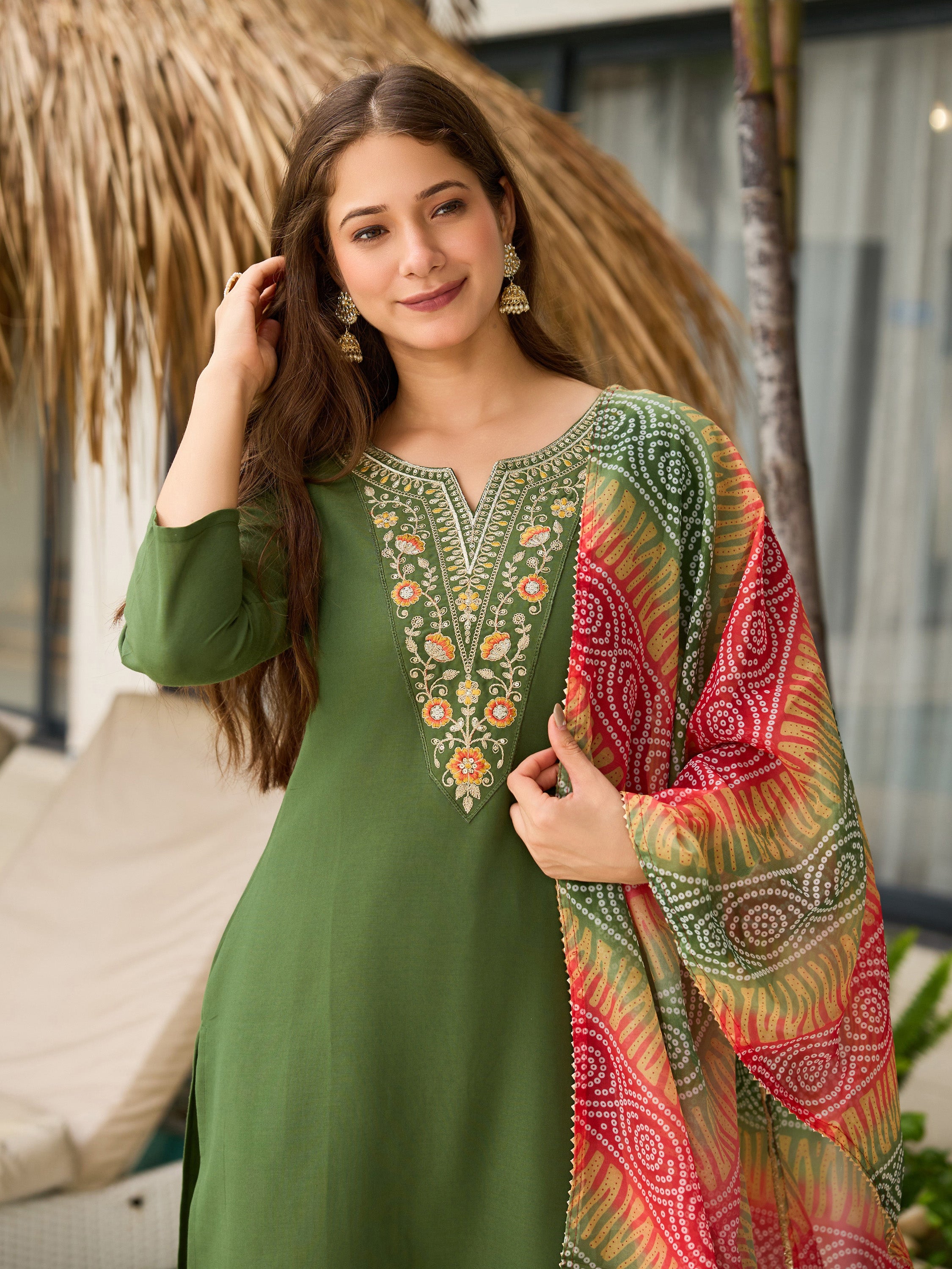 Model smiling, adjusting hair, showcasing TRENDBUY Mahendi green kurta set with dupatta, by pool.