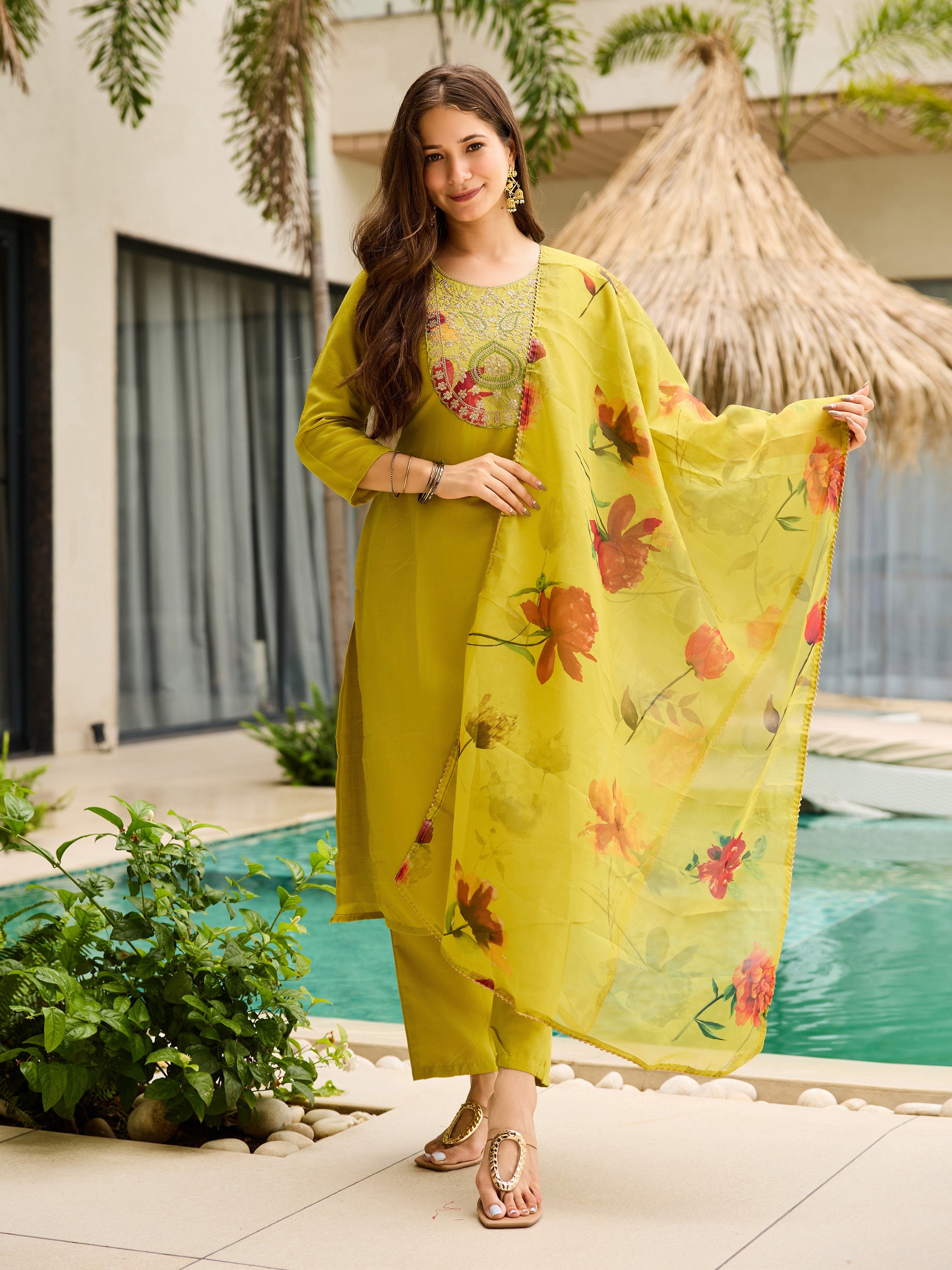 Model smiling in a Liril Green Rayon Kurti Set with floral taby dupatta, posing gracefully by a resort pool.