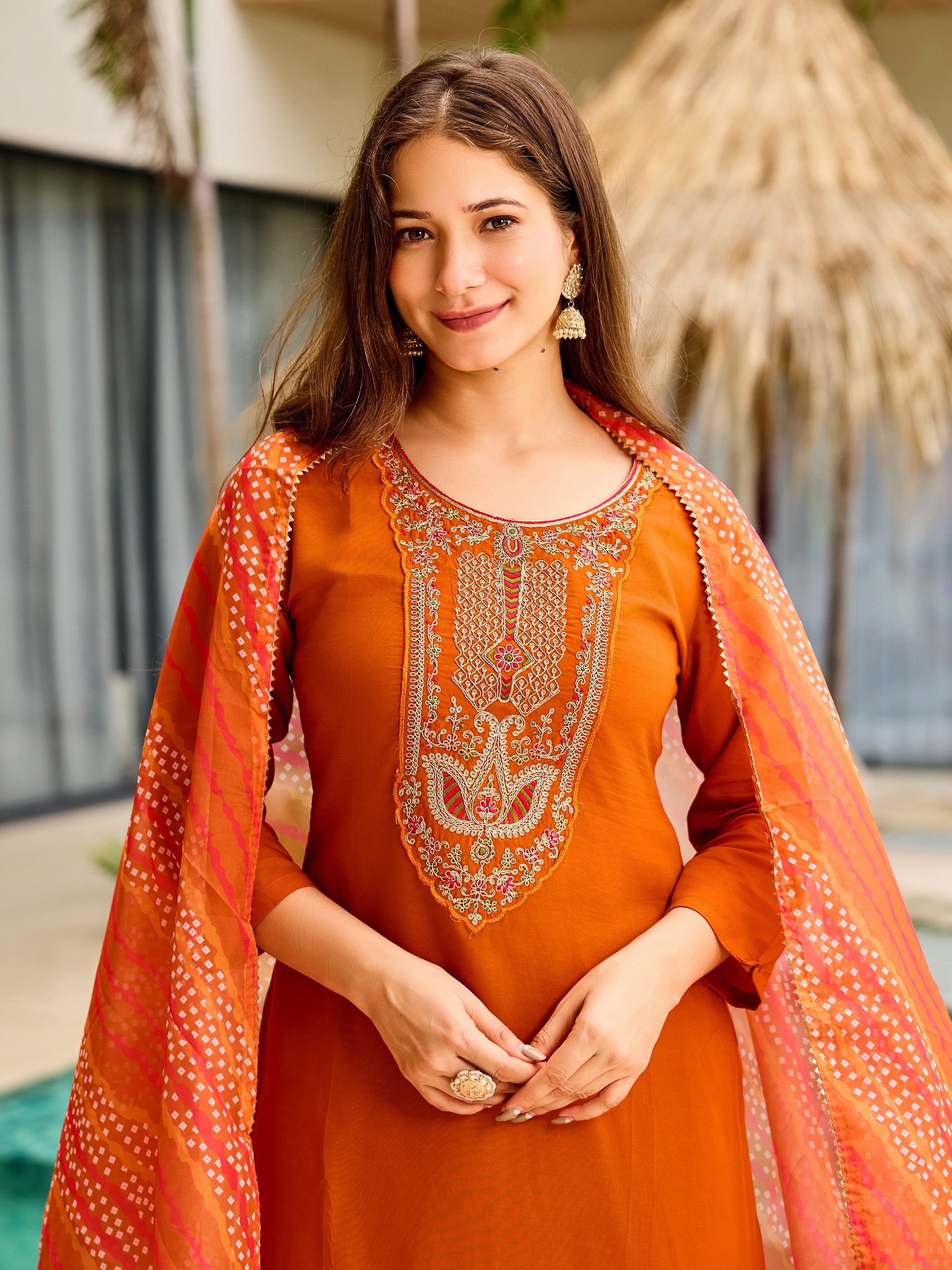 Model in rust orange embroidered kurta set, smiling, with the vibrant Taby dupatta draped stylishly over shoulders