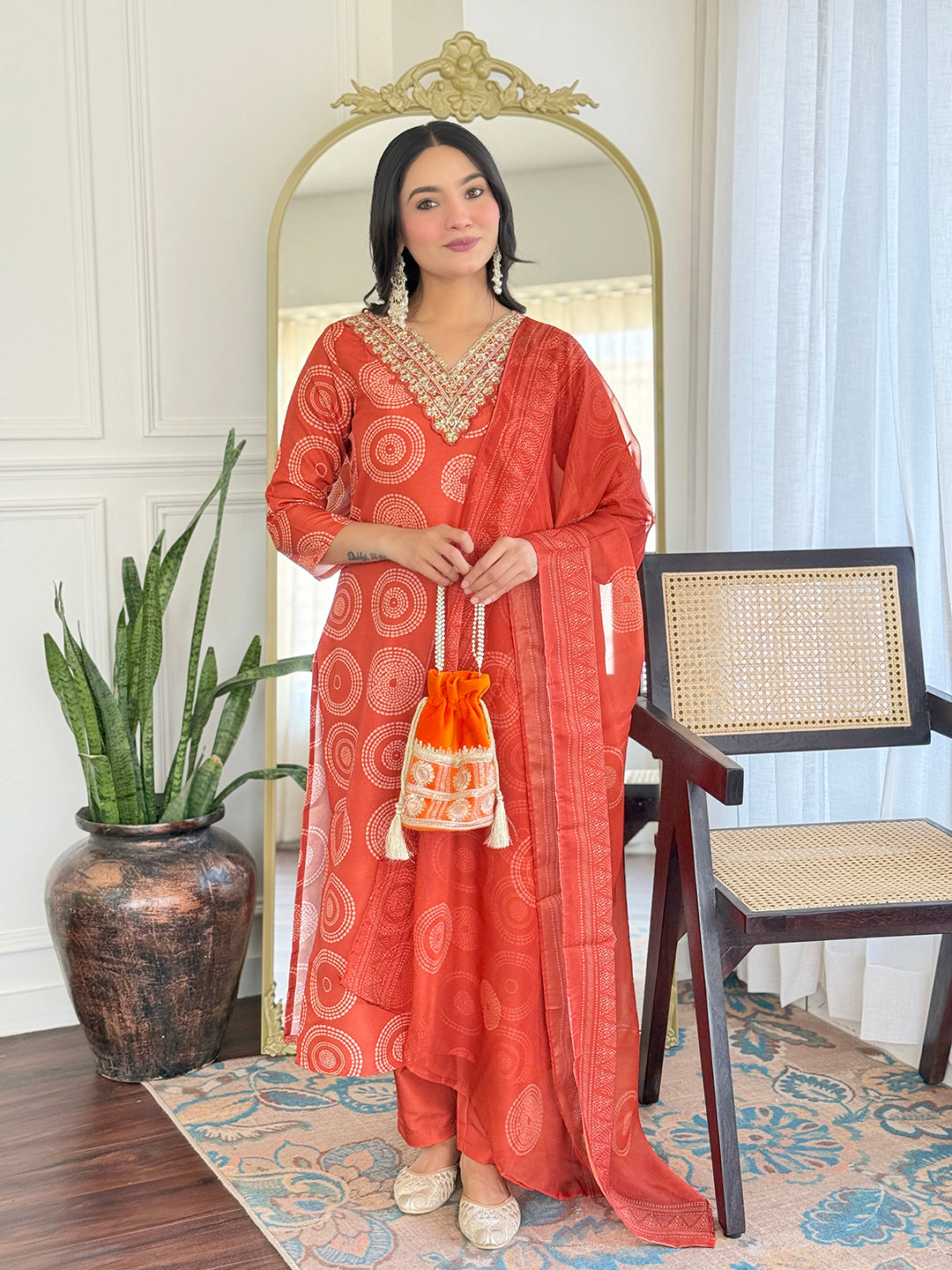 TRENDBUY model showcasing D732 orange rayon kurti set with geometric print, embroidery, and a matching dupatta, holding a potli bag.