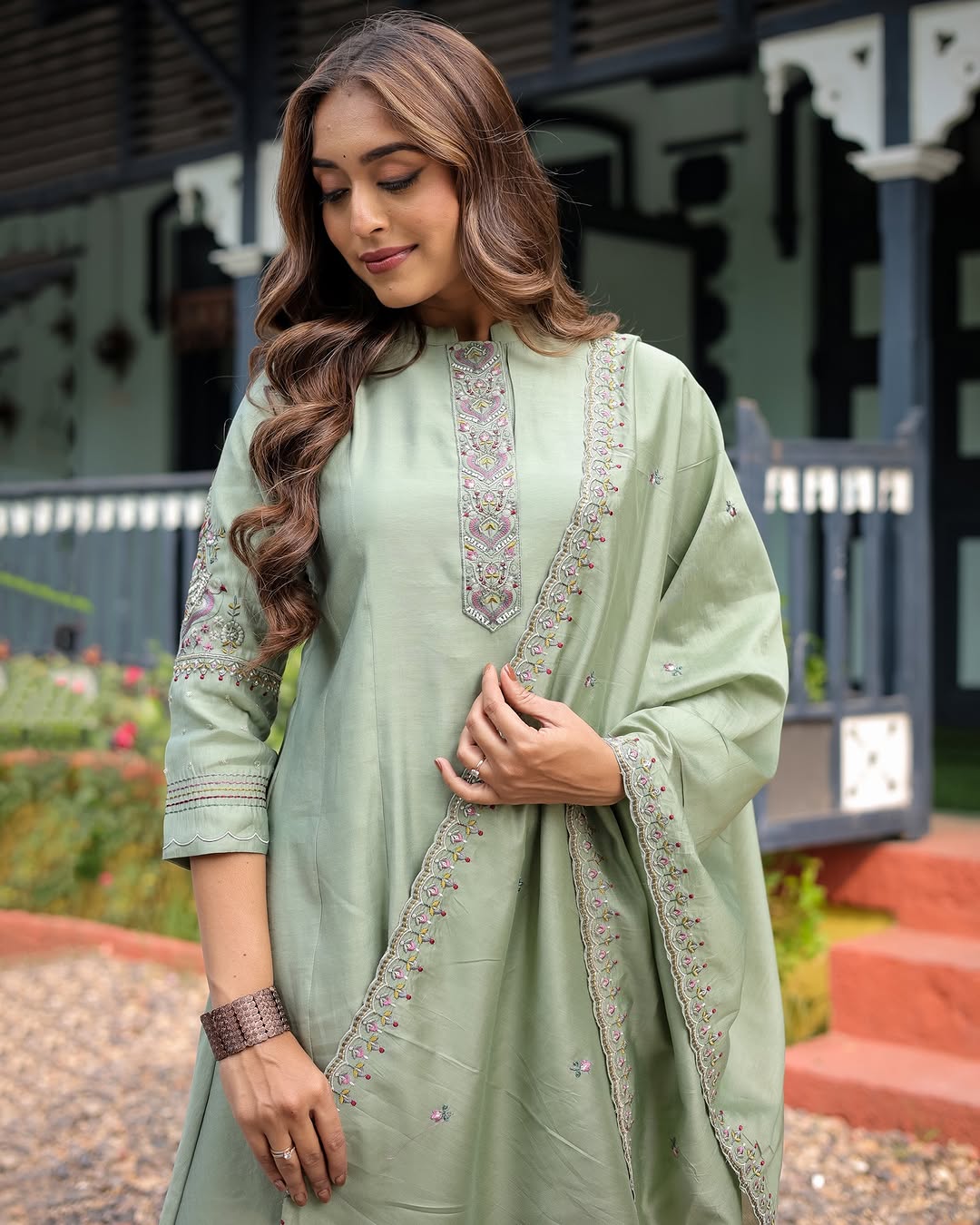 Close-up of a woman in the TRENDBUY Olive Green Kurta Set, showing the detailed embroidery on the sleeves and dupatta border, hands adjusting the fabric.