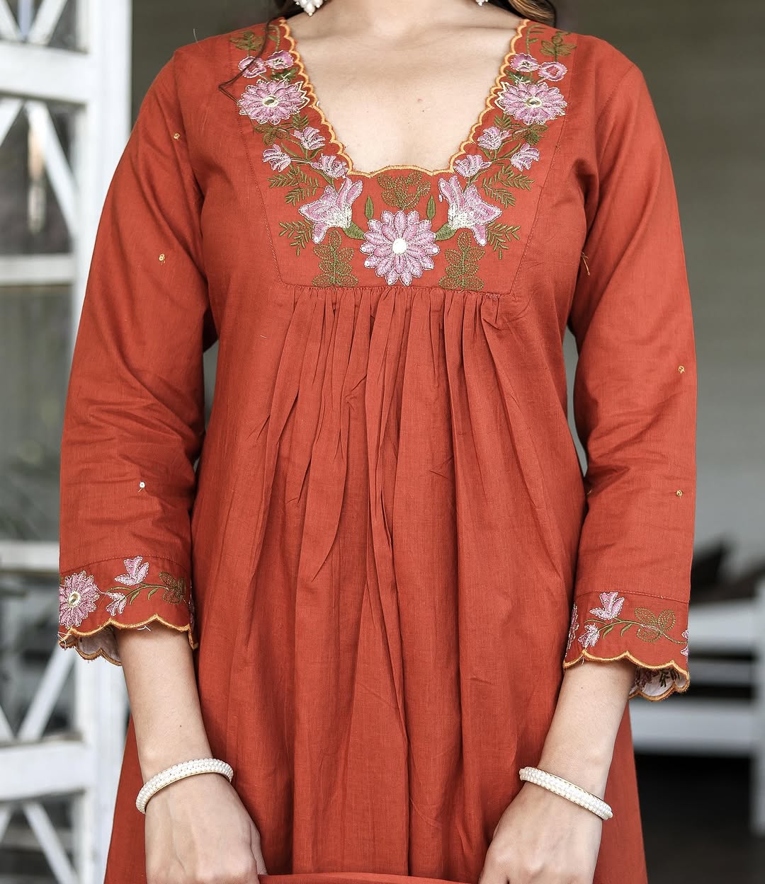 Close-up of orange rayon slub kurti with intricate floral embroidery on the sweetheart neckline and sleeves.