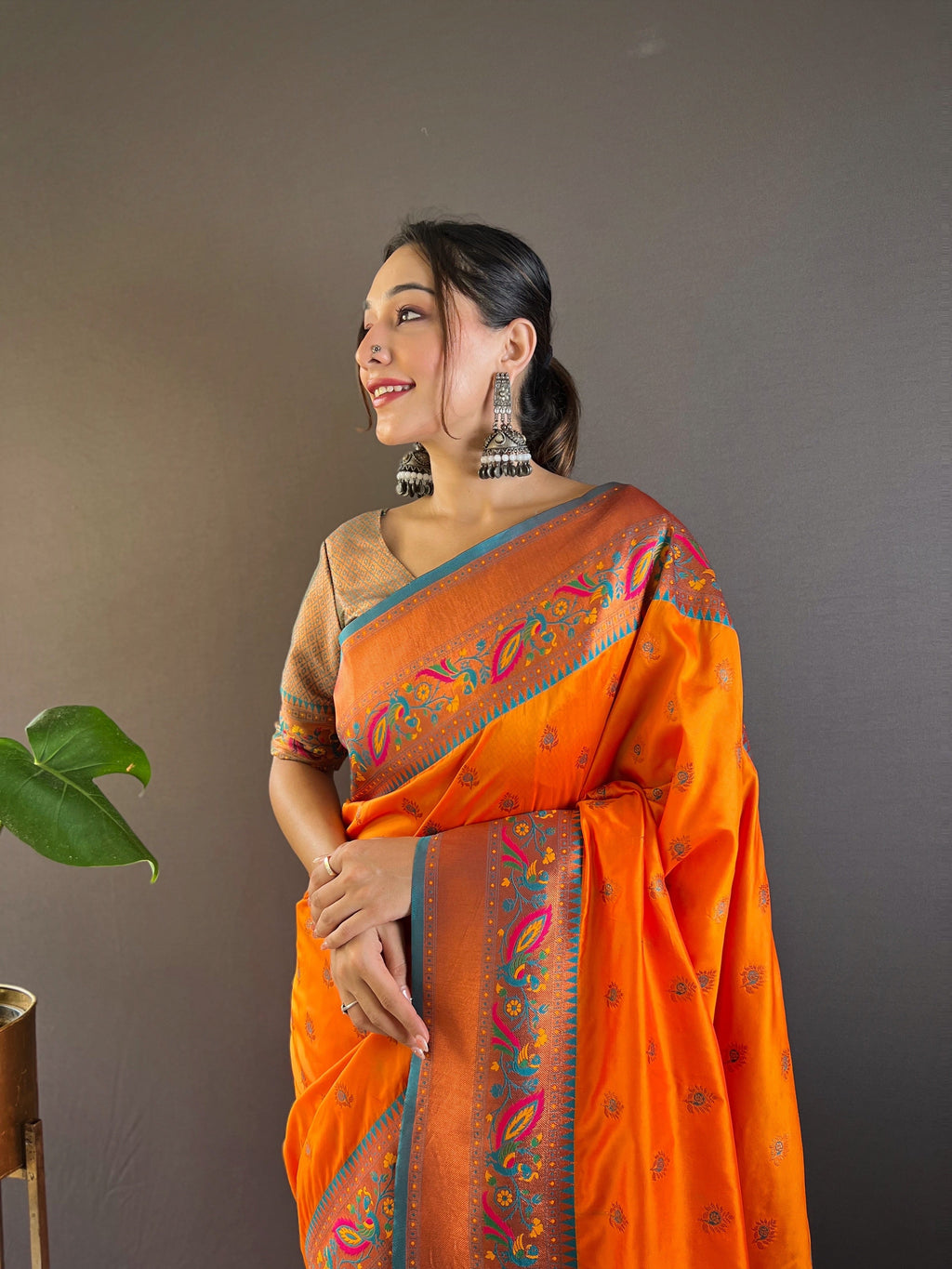 Close-up of intricate gold Zari weaving on vibrant orange silk fabric